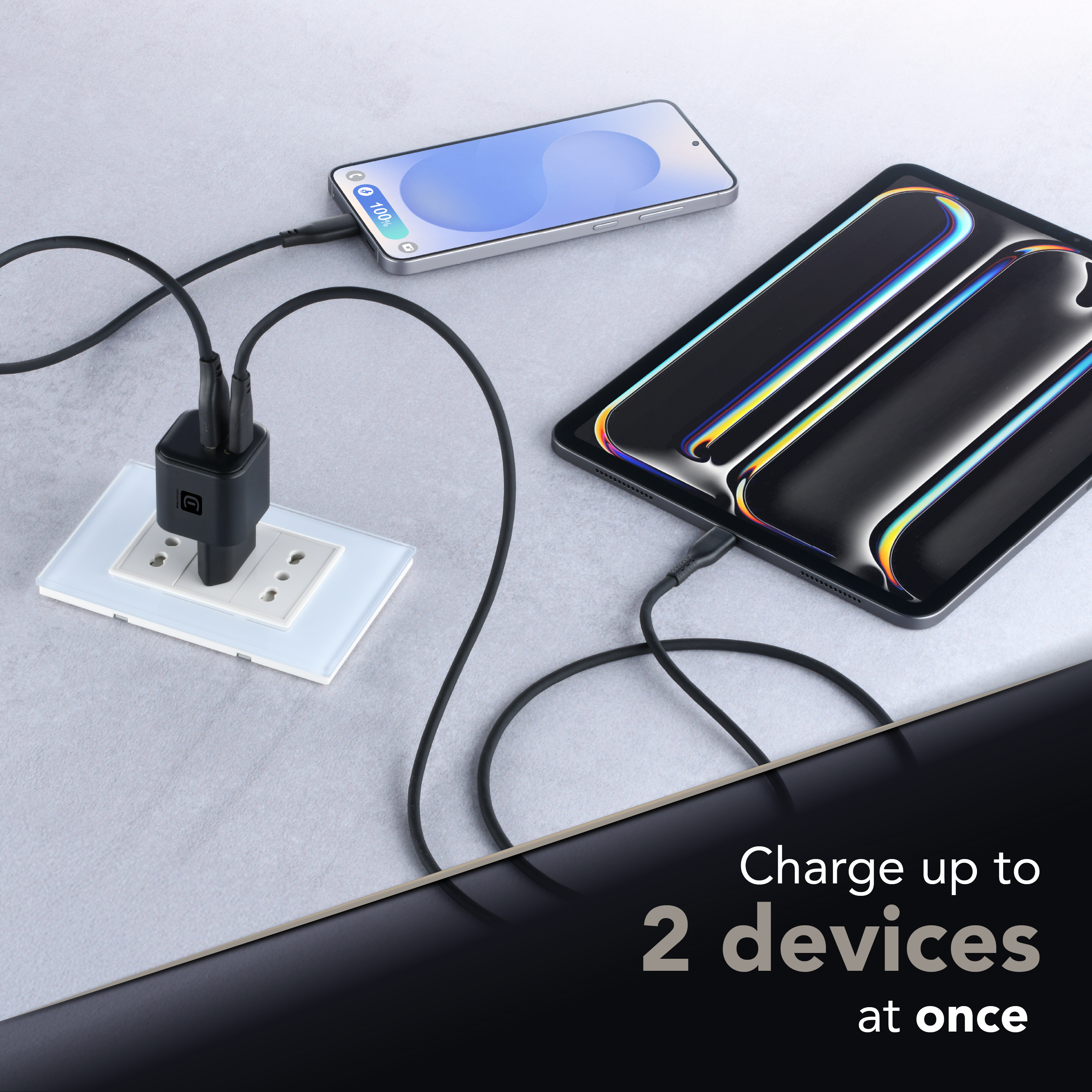 Cargador CellularLine conectado cargando móvil y tablet, texto “Charge up to 2 devices at once”.