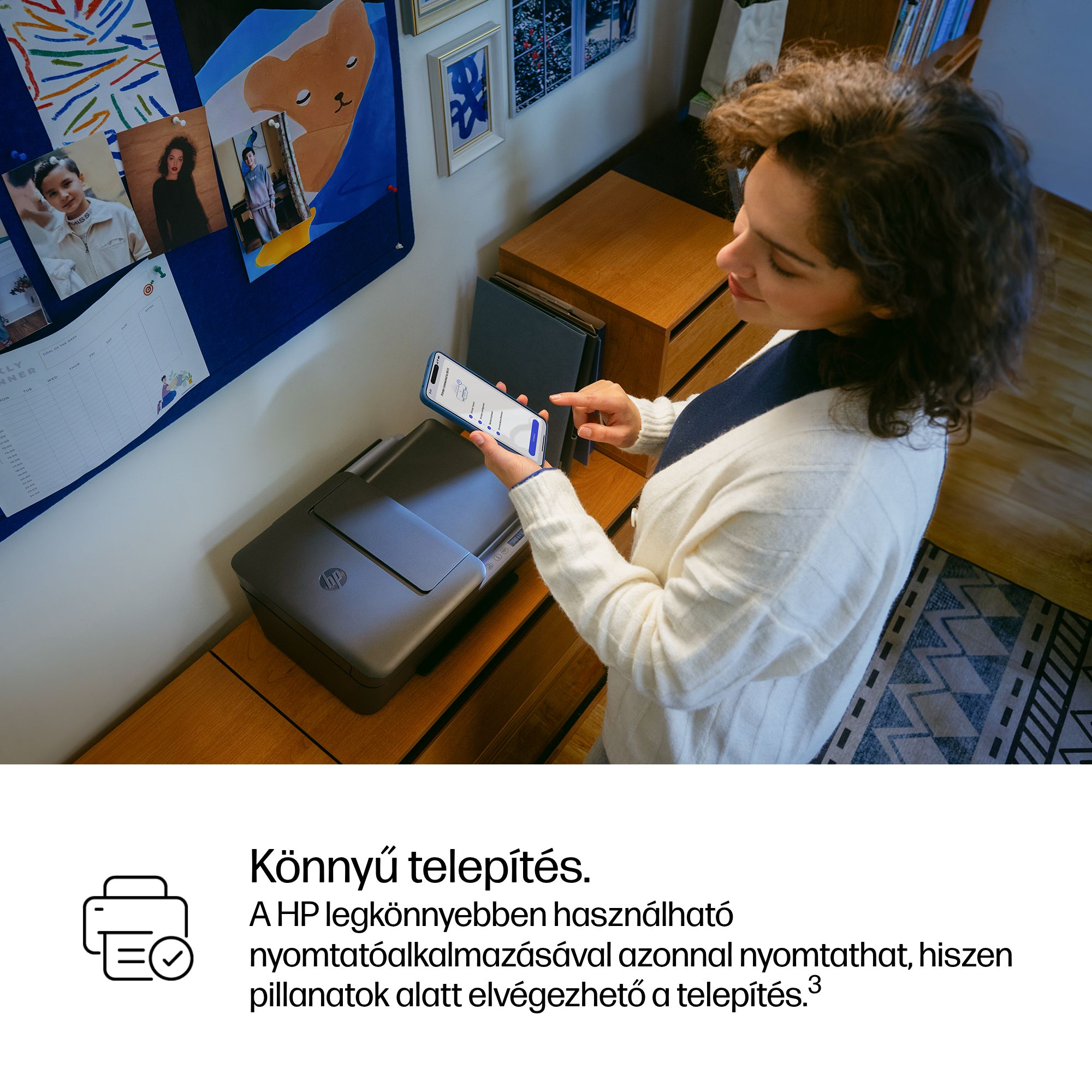 Nő HP nyomtatót állít be telefonnal. Fotós tábla a háttérben.