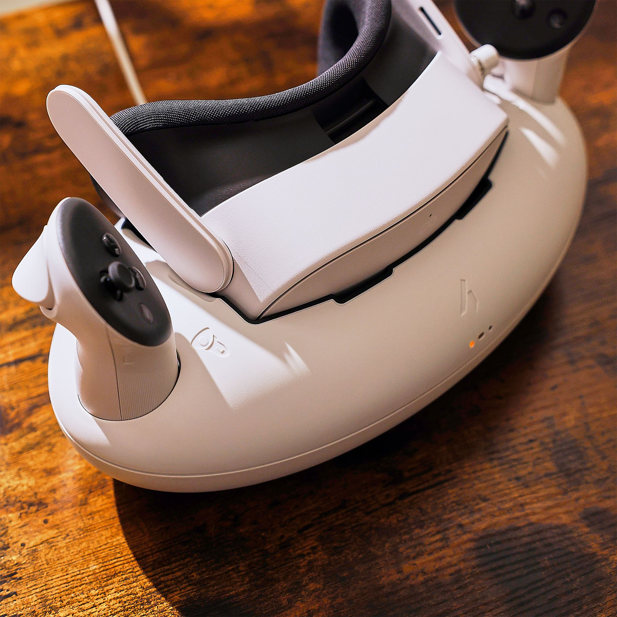 Weiße VR-Brille mit Controller auf Holztisch.