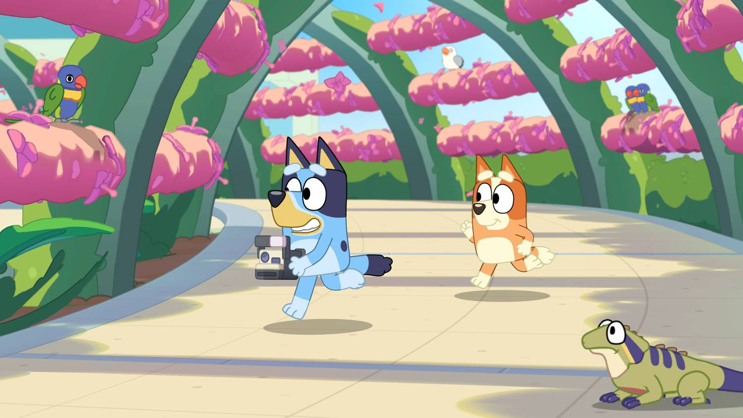 Bluey y Bingo corren junto a un dinosaurio, con loros en un paisaje alienígena rosa.