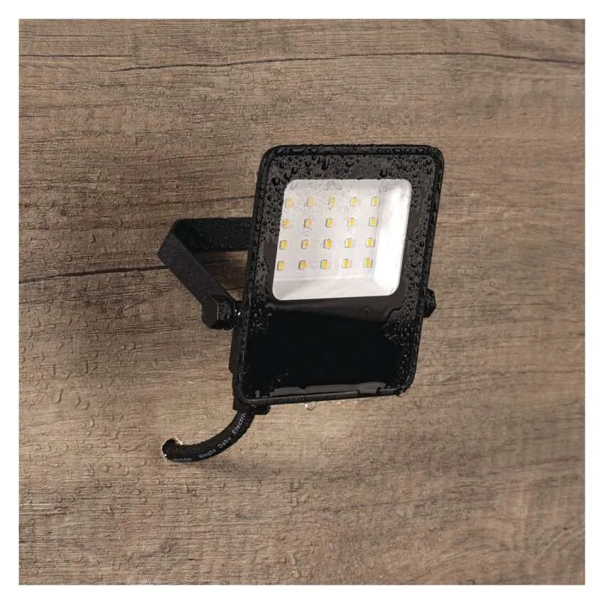 Egy fekete LED-es reflektor vízcseppekkel, fa hátlapon.