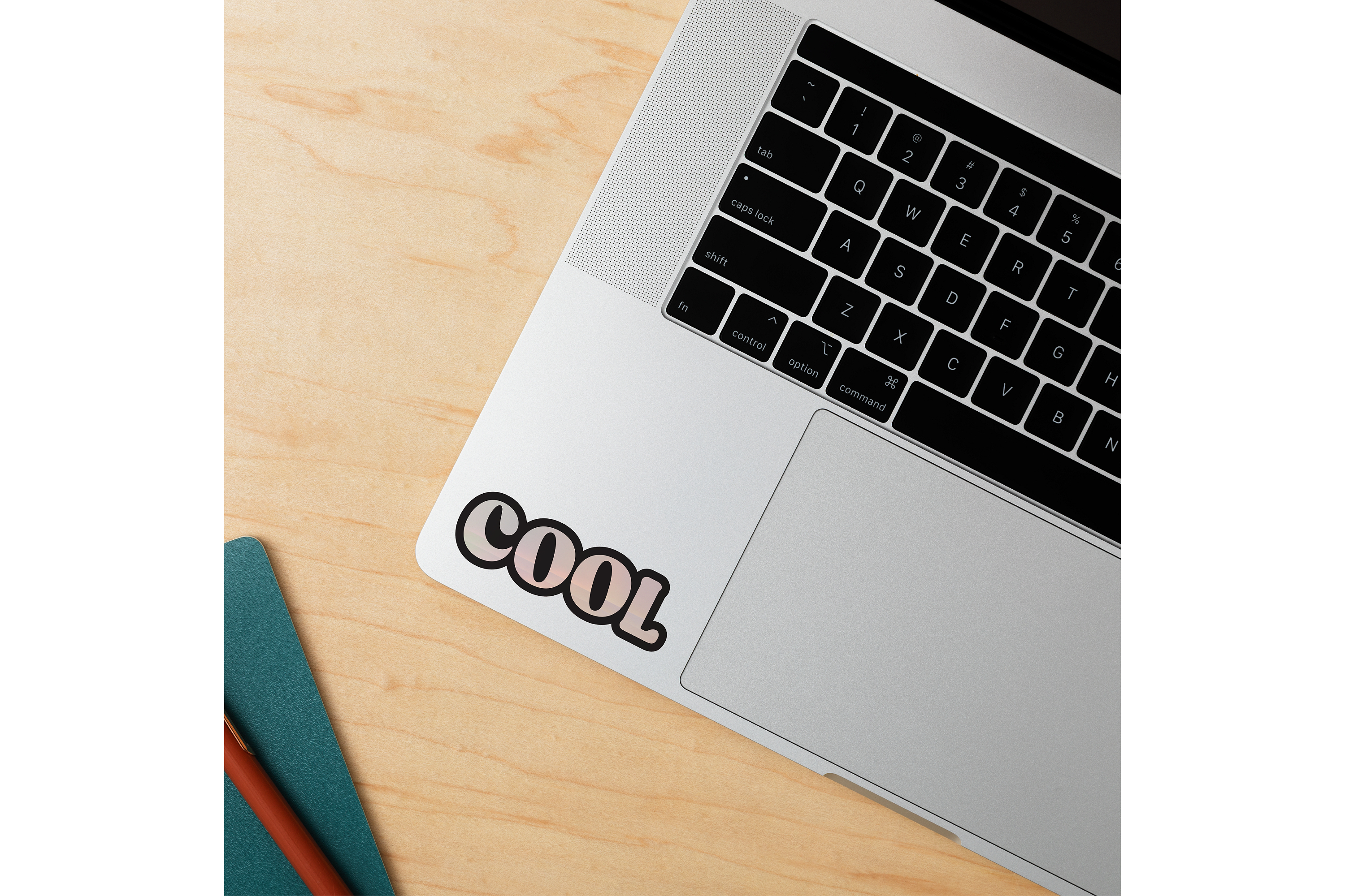 Un portátil sobre un escritorio de madera con un adhesivo "COOL".