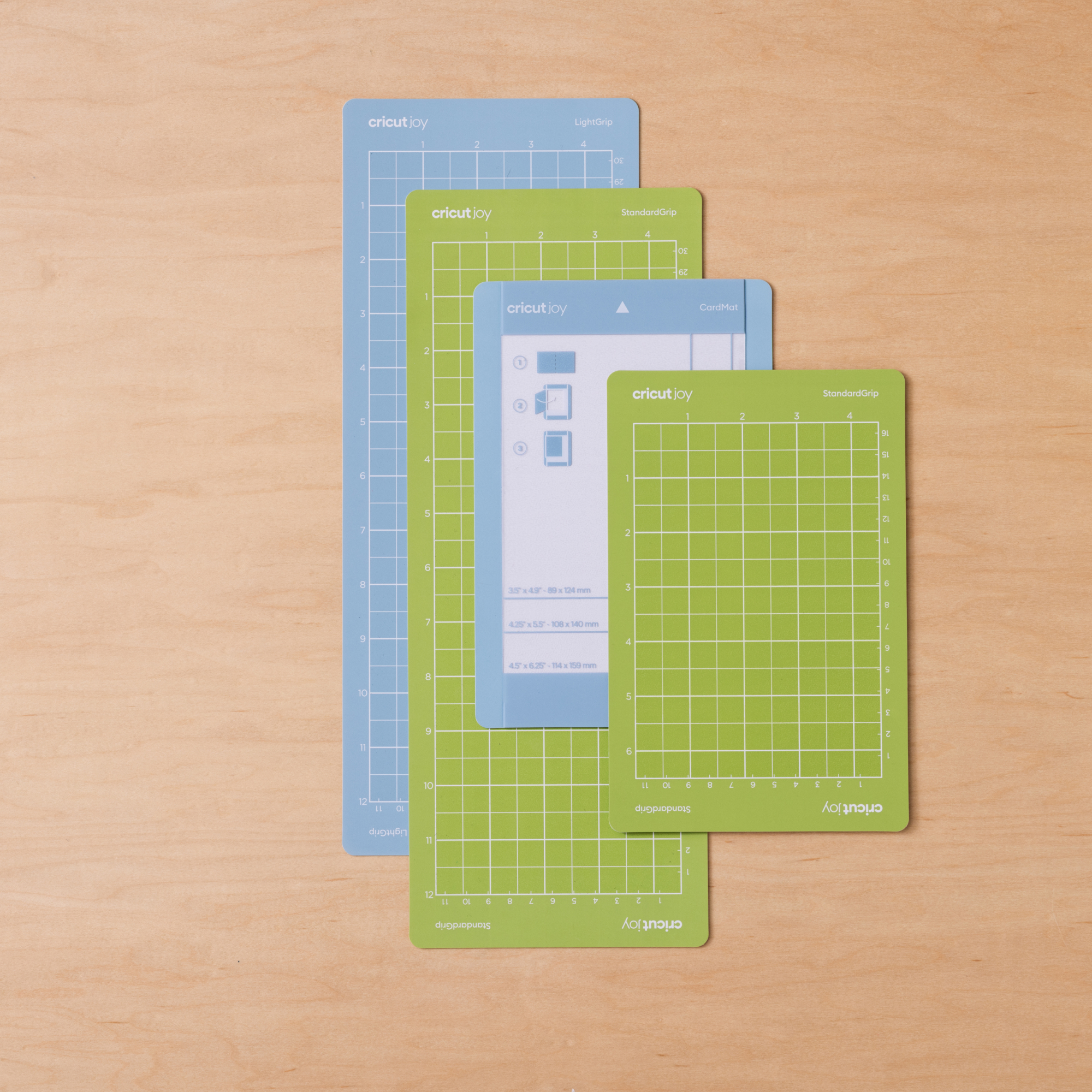Tres tapetes de corte Cricut Joy, azules y verdes, sobre madera.