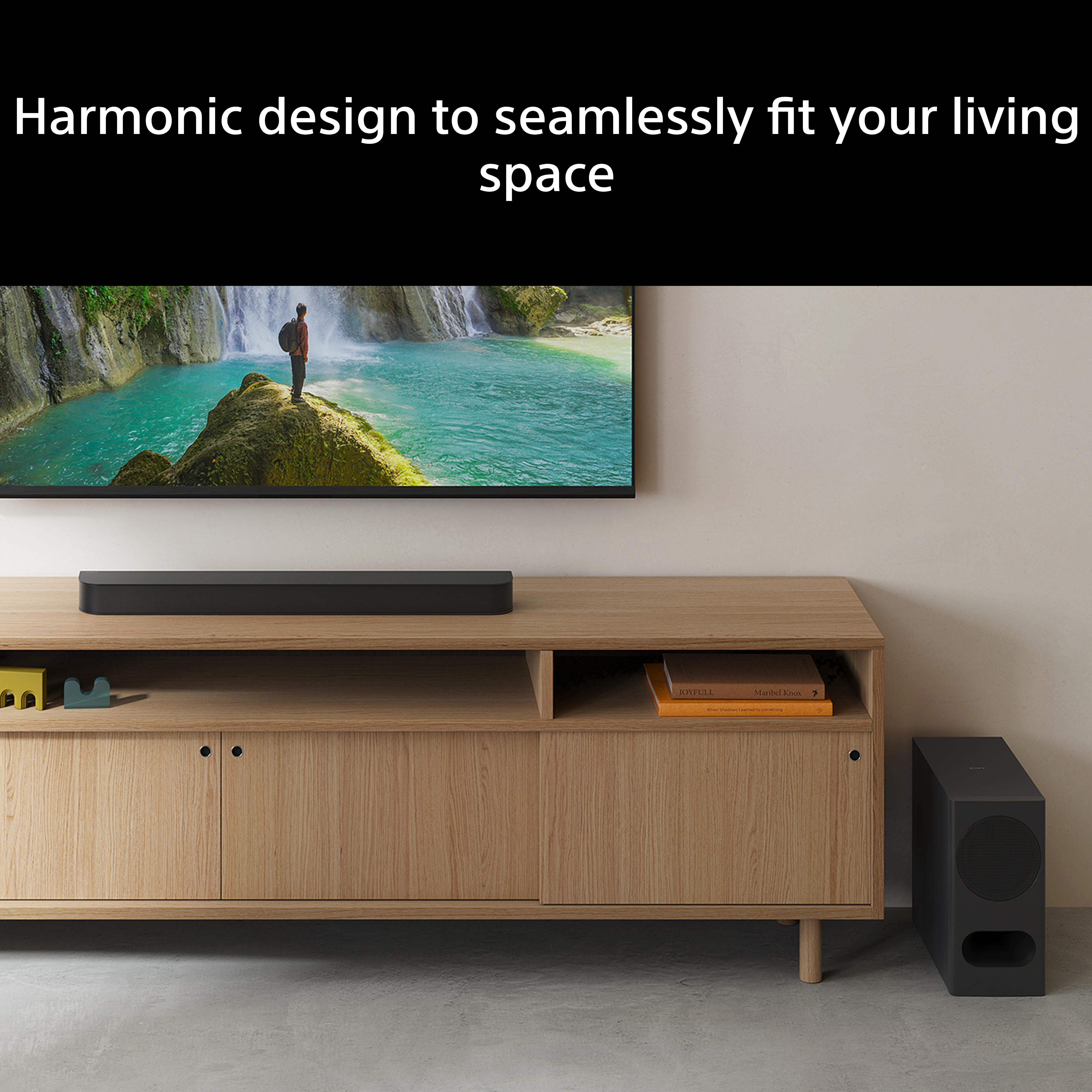 Un uomo su una roccia davanti a una cascata, con soundbar e subwoofer vicini.