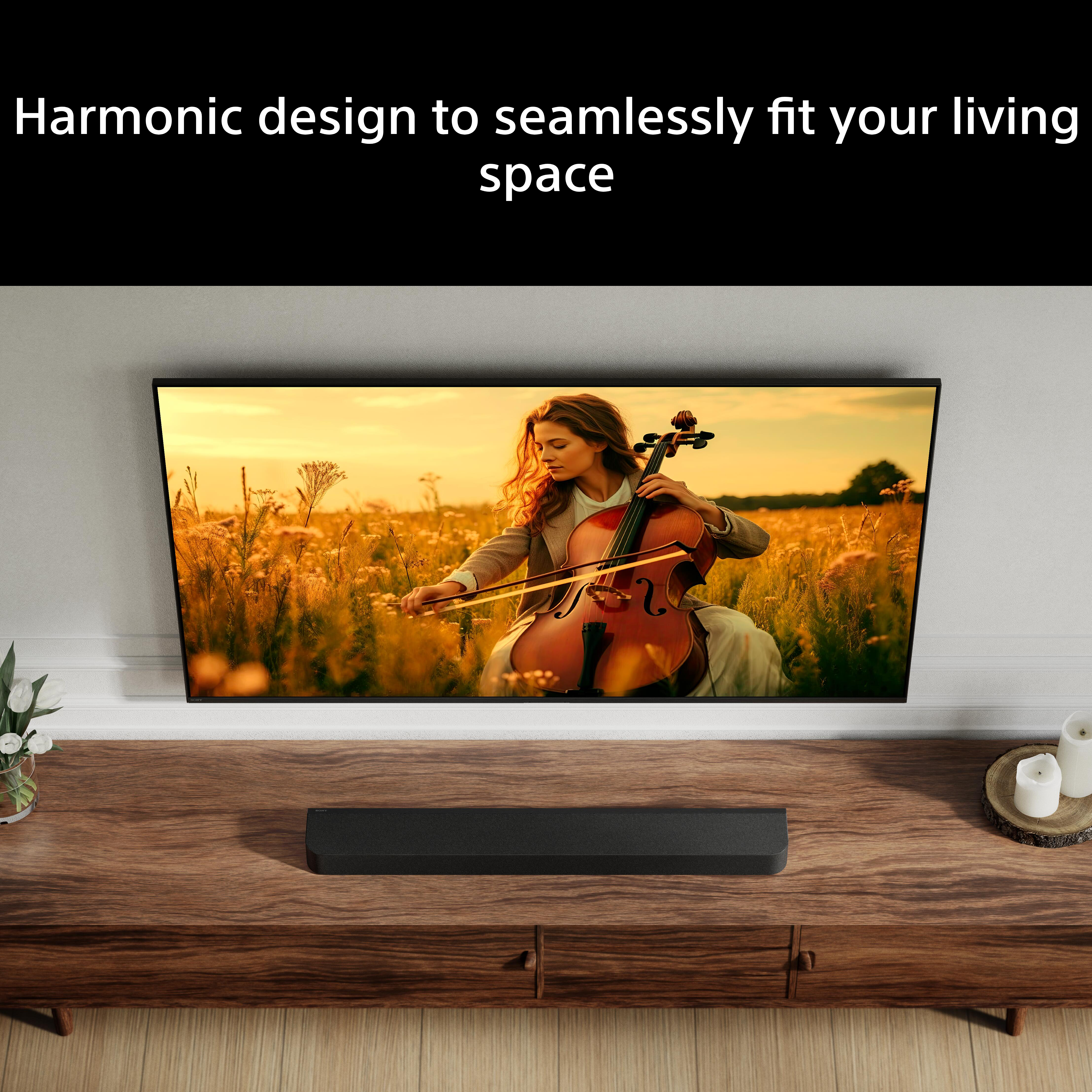 Una donna suona il violoncello in un campo al tramonto. Una TV mostra la scena.