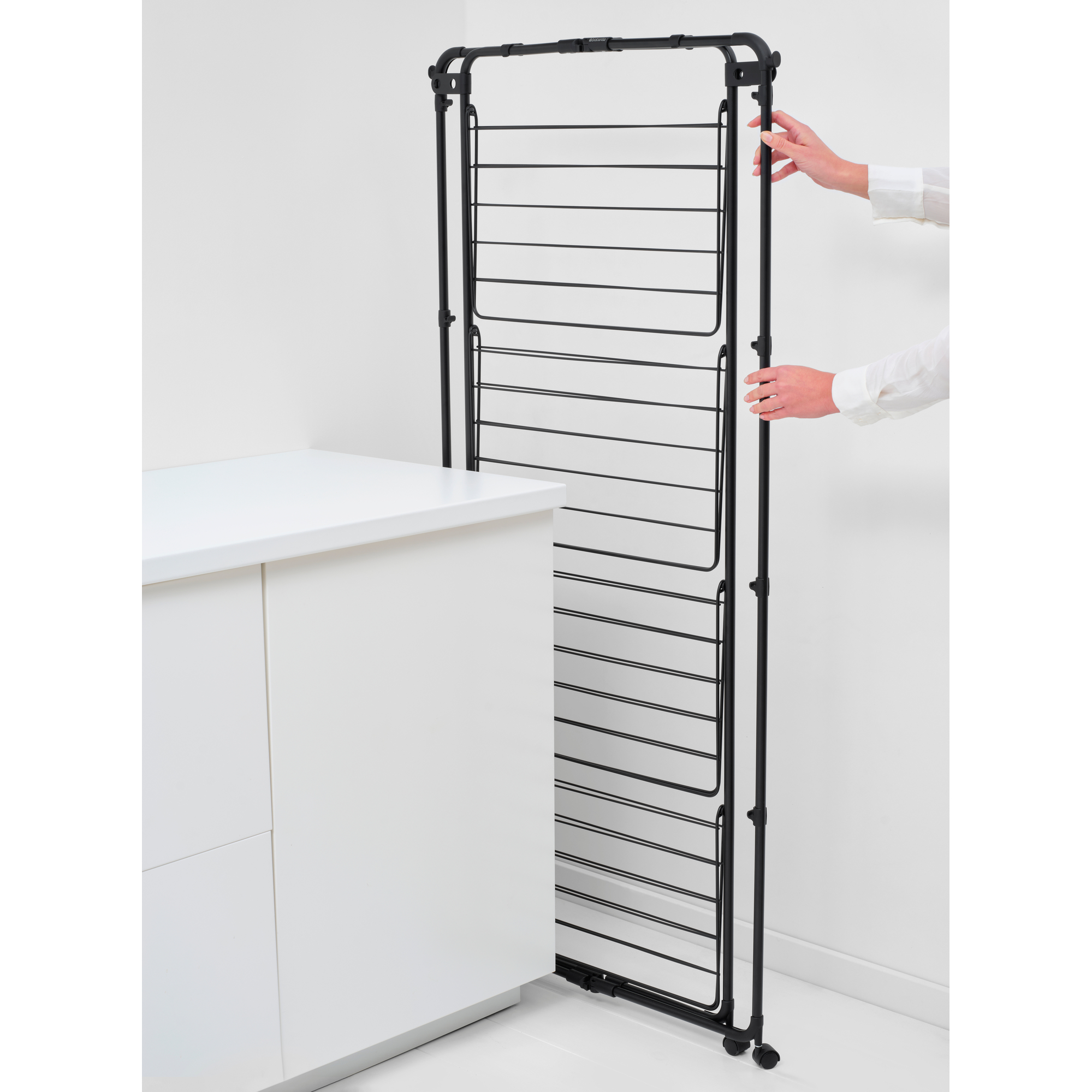Ein schwarzer Wäscheständer steht neben einem weißen Schrank.
