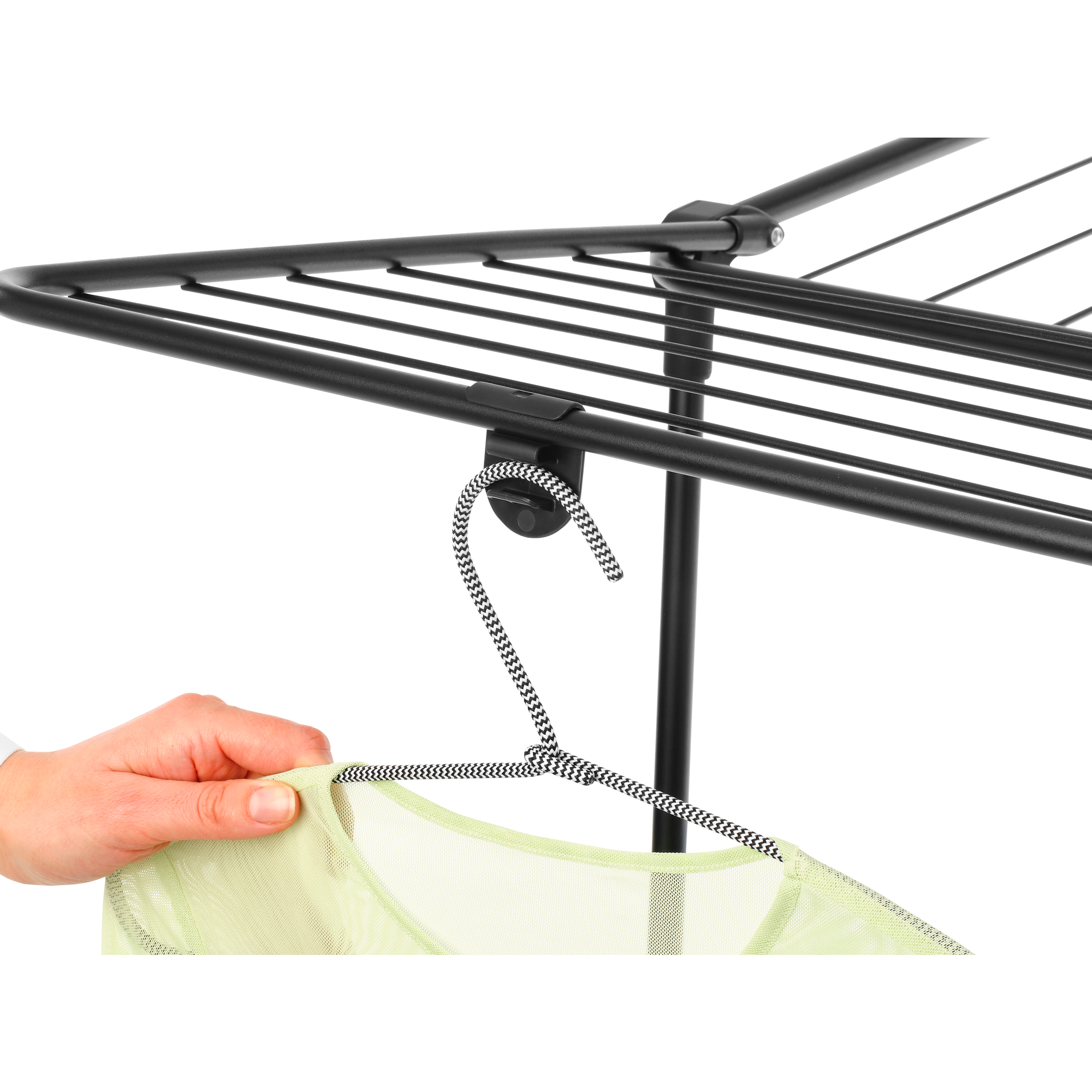 Eine Hand hält ein hellgrünes Kleidungsstück an einem schwarz-weiß gemusterten Kleiderbügel.