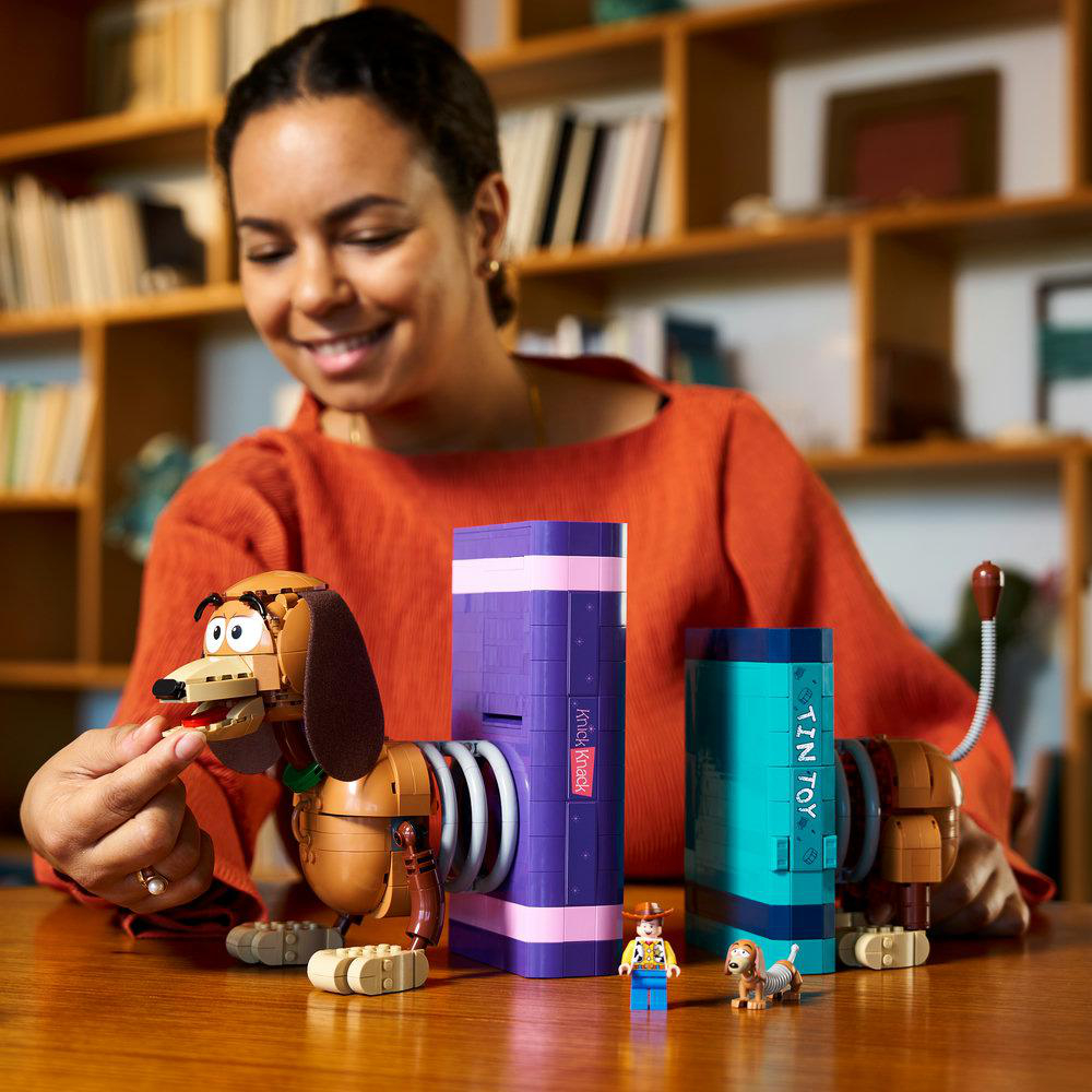 Frau baut Slinky Dog Lego, Woody und Buzz Lightyear Figuren.