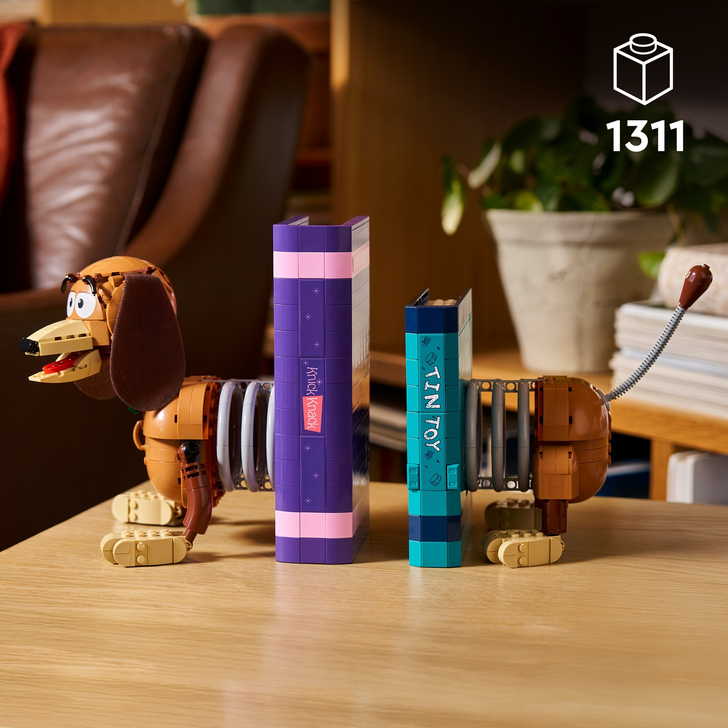 Un cane Slinky LEGO è su un tavolo di legno accanto a due mattoncini LEGO a forma di libro.