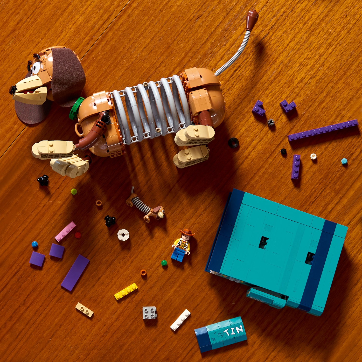Un cane Slinky Lego giace su un tavolo di legno con blocchi.
