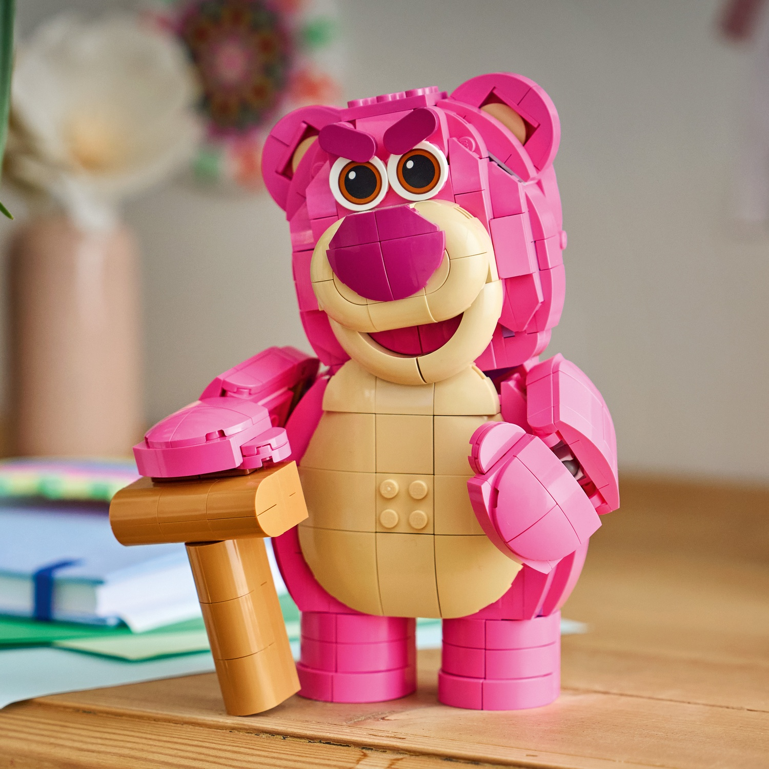 Orso Lego rosa tiene un martello marrone. Ci sono libri sul tavolo.