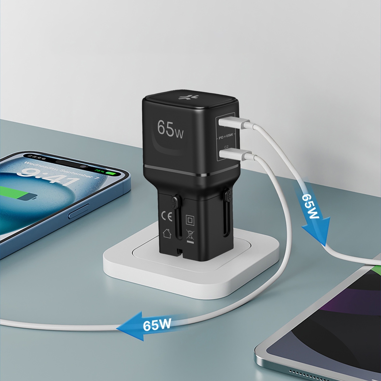 Un adattatore nero da 65W carica uno smartphone e un tablet.