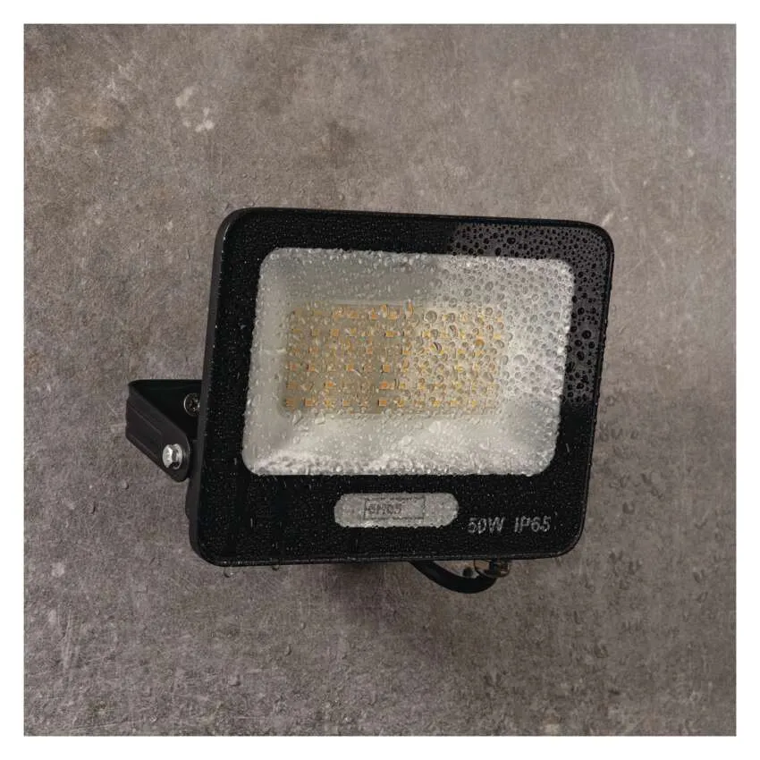 Fekete LED-es reflektor vízcseppekkel az üvegen, szürke háttérrel.