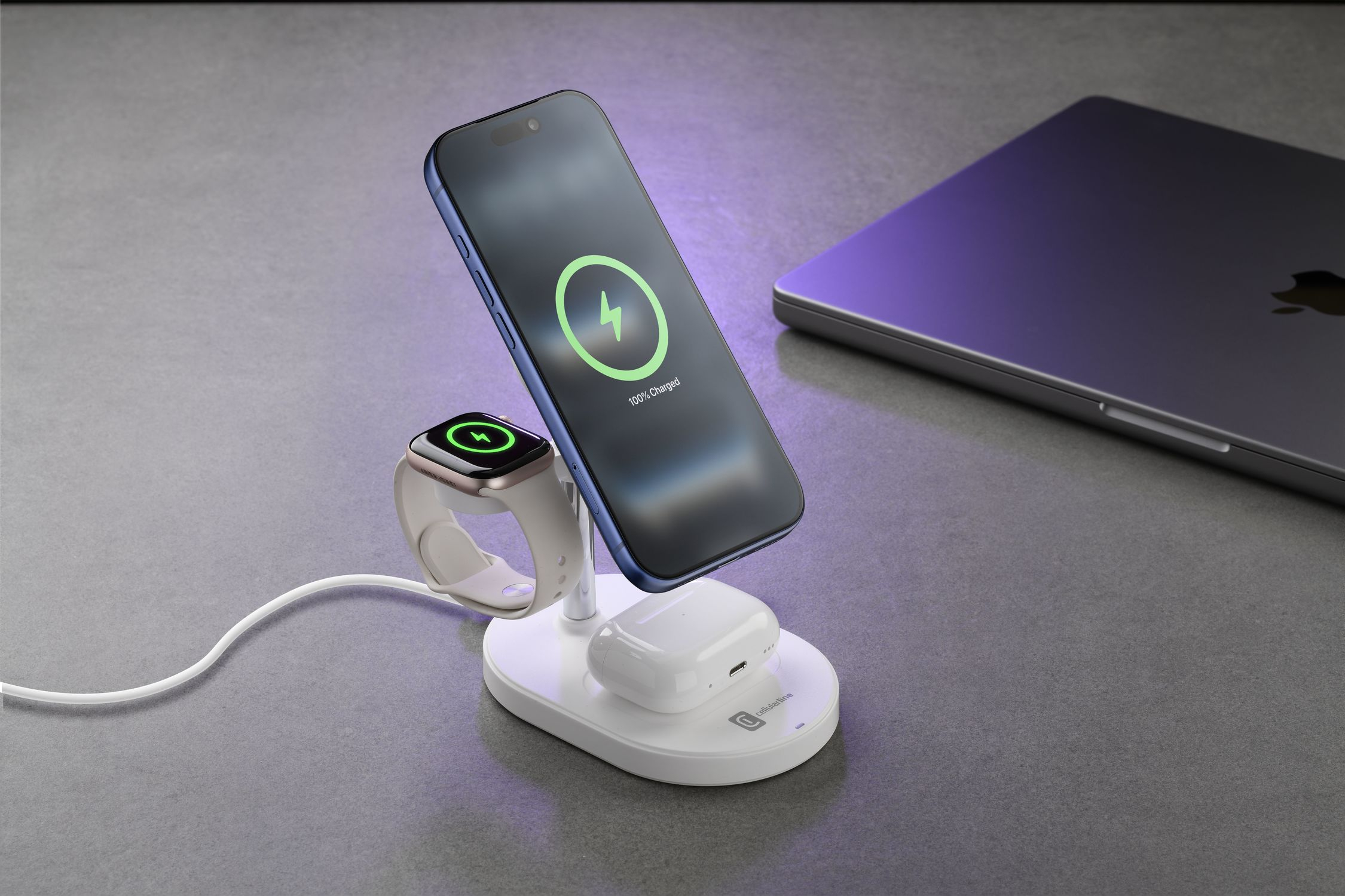 Un soporte de carga con iPhone, Apple Watch y AirPods sobre una superficie gris.