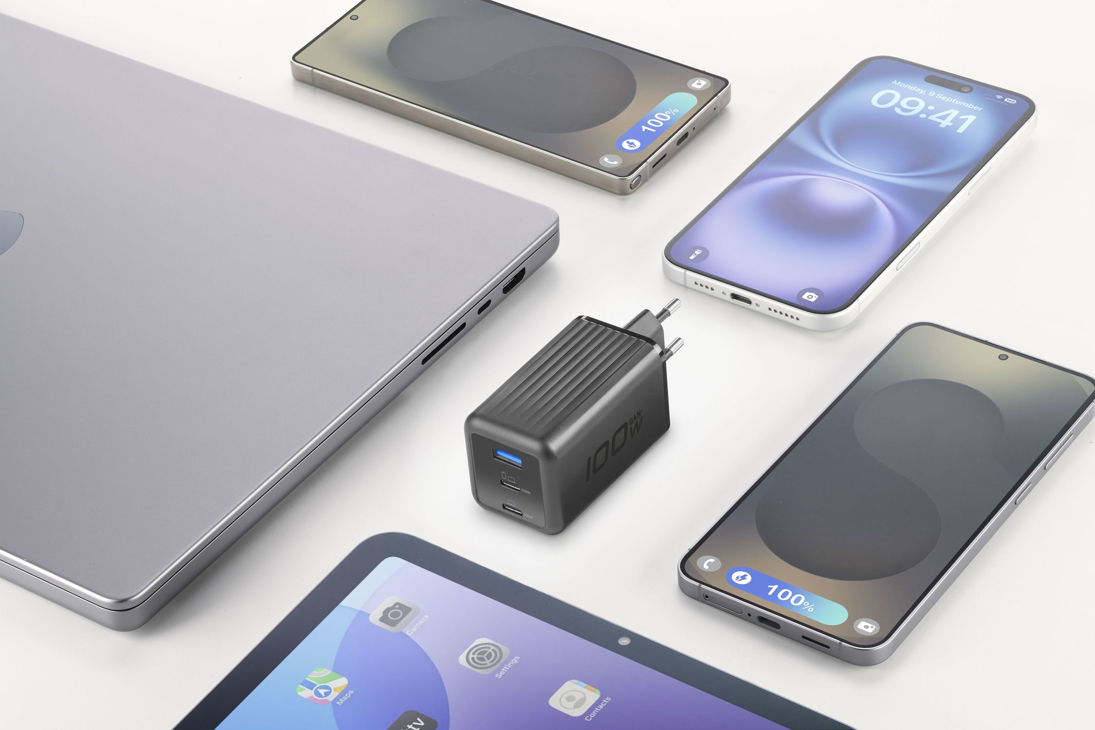 Portátil, cargador y tres teléfonos inteligentes sobre fondo blanco.