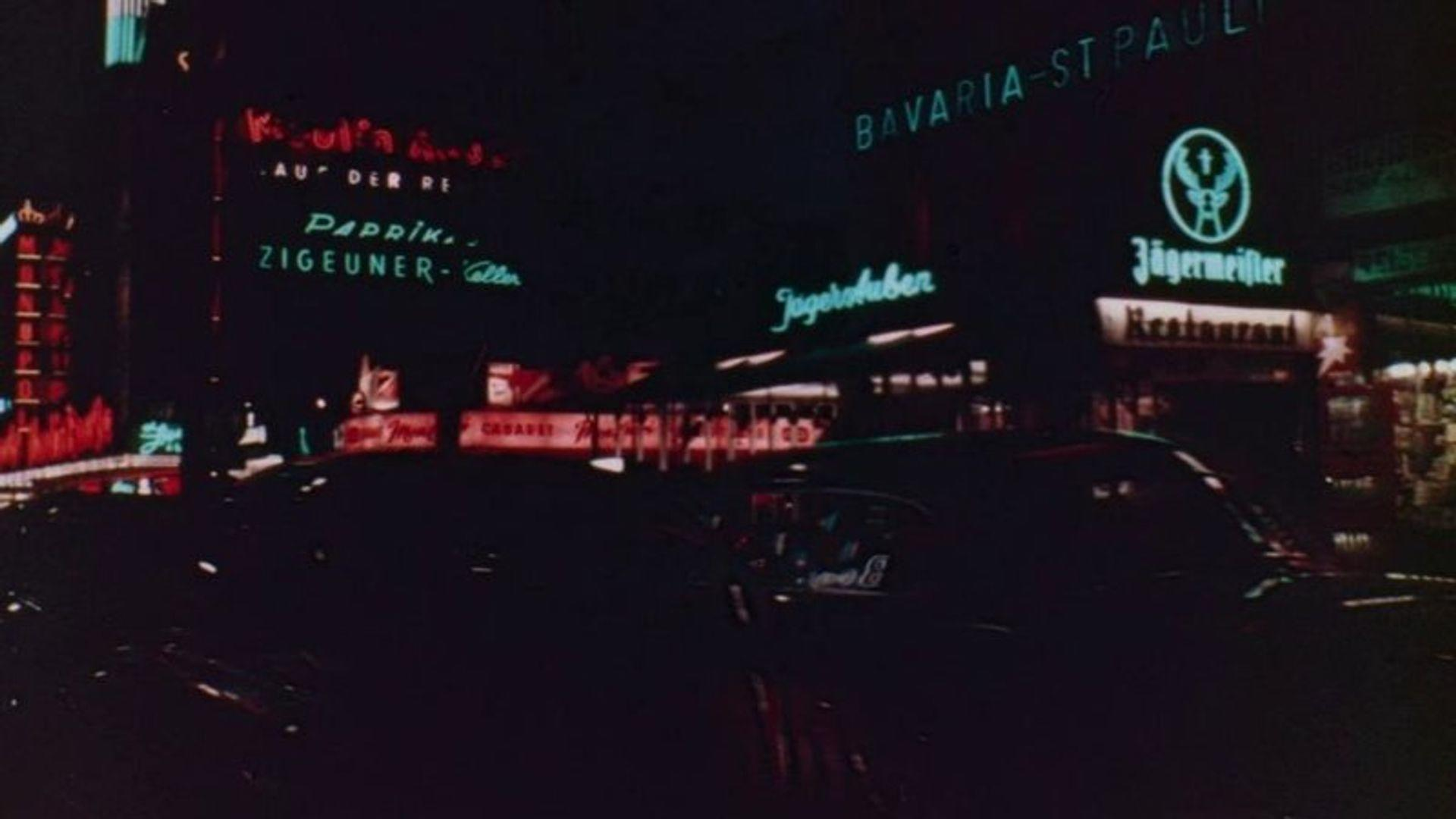 Nachts in der Stadt mit vielen Neonschildern wie Jägermeister und Cabaret.