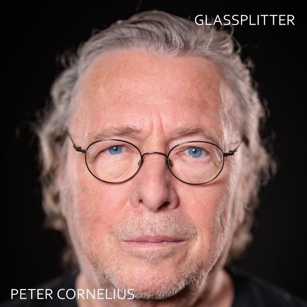 Porträt eines älteren Mannes mit Brille und grauem Haar vor schwarzem Hintergrund.