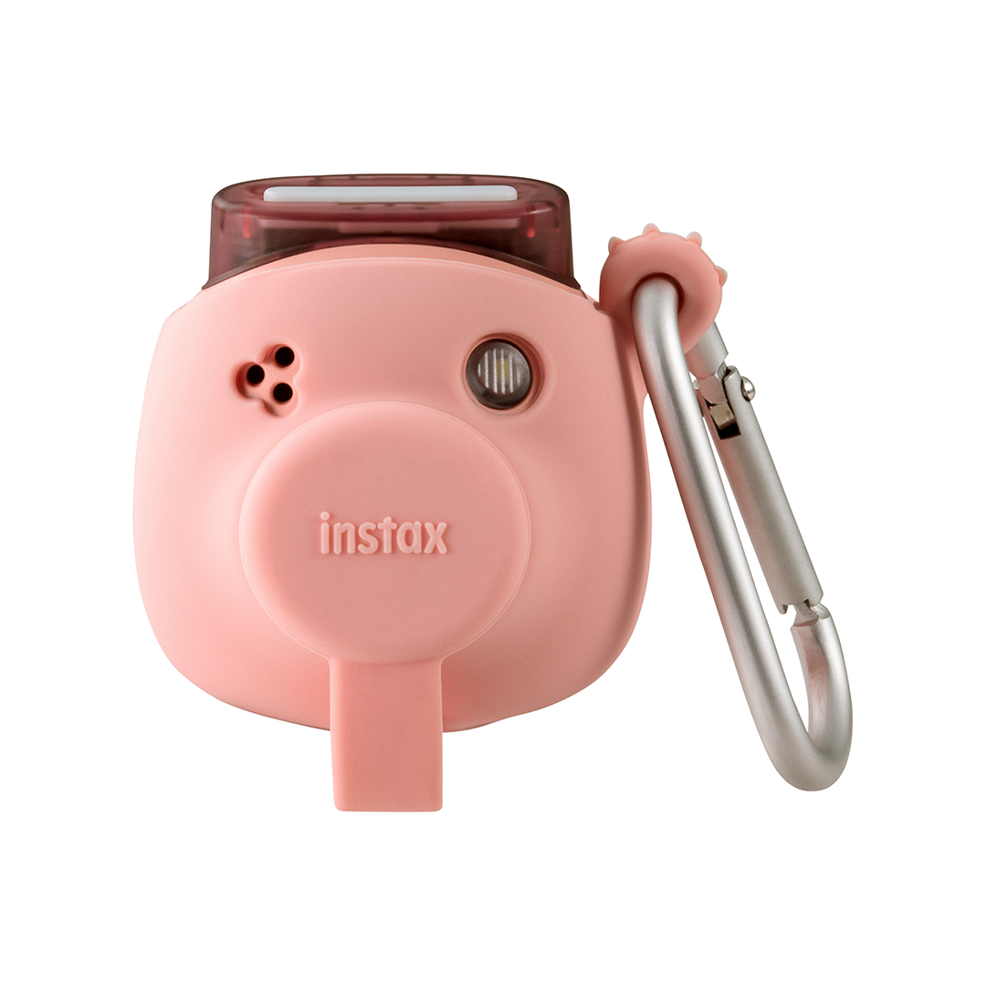 Sağ tarafında gümüş bir karabina bulunan pembe bir Instax kamera.