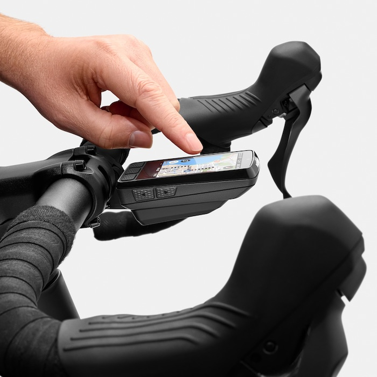 A man uses a finger to operate a bike navigation device. Black handlebars and shifters.