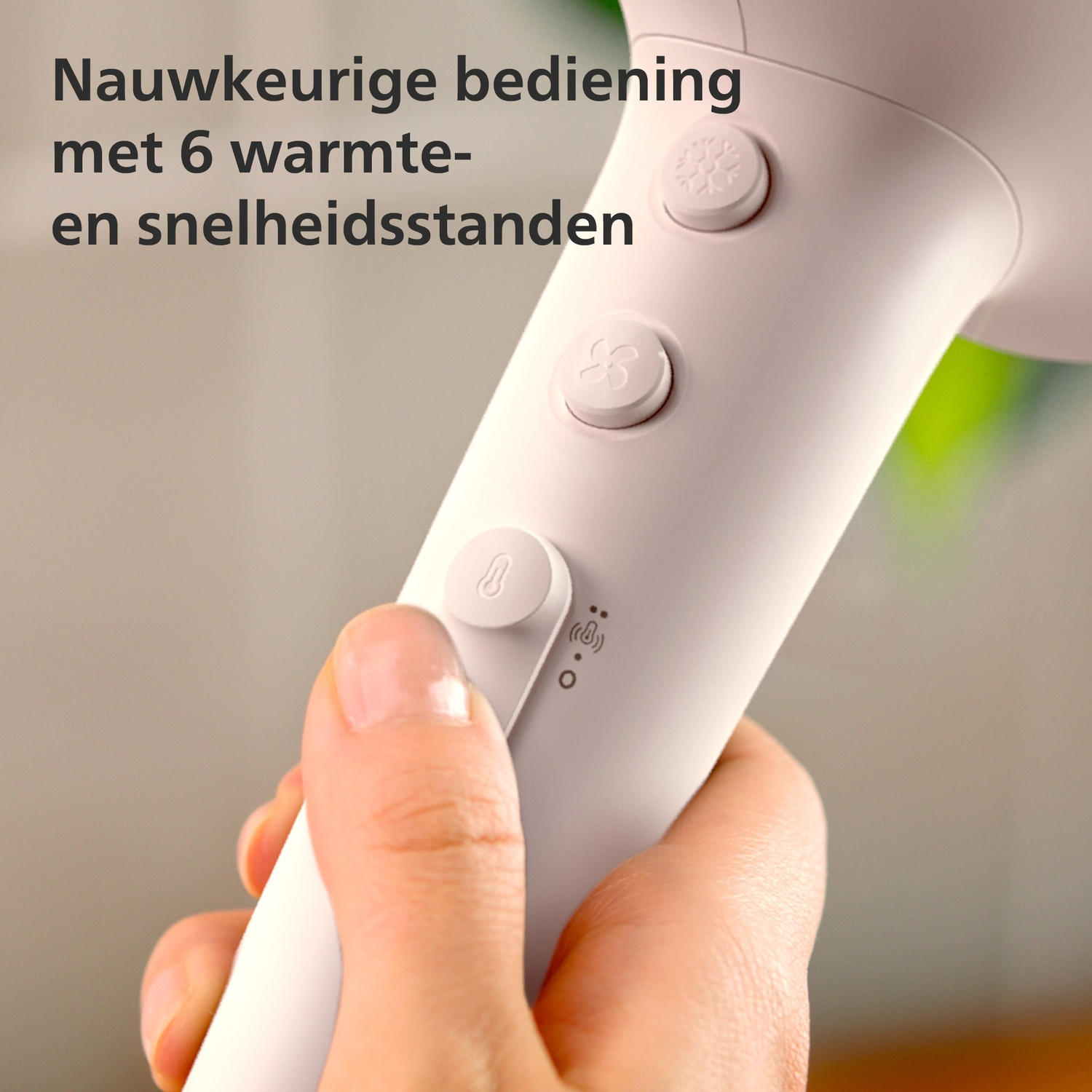 Een hand houdt een witte haardroger vast met bedieningsknoppen en pictogrammen.