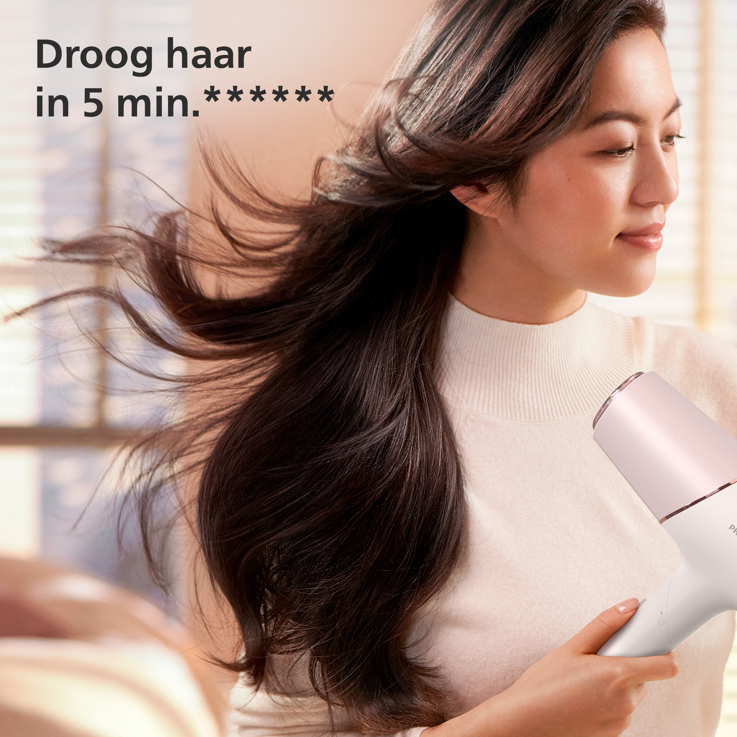 Vrouw met lang donker haar droogt haar met een witte en roze föhn.