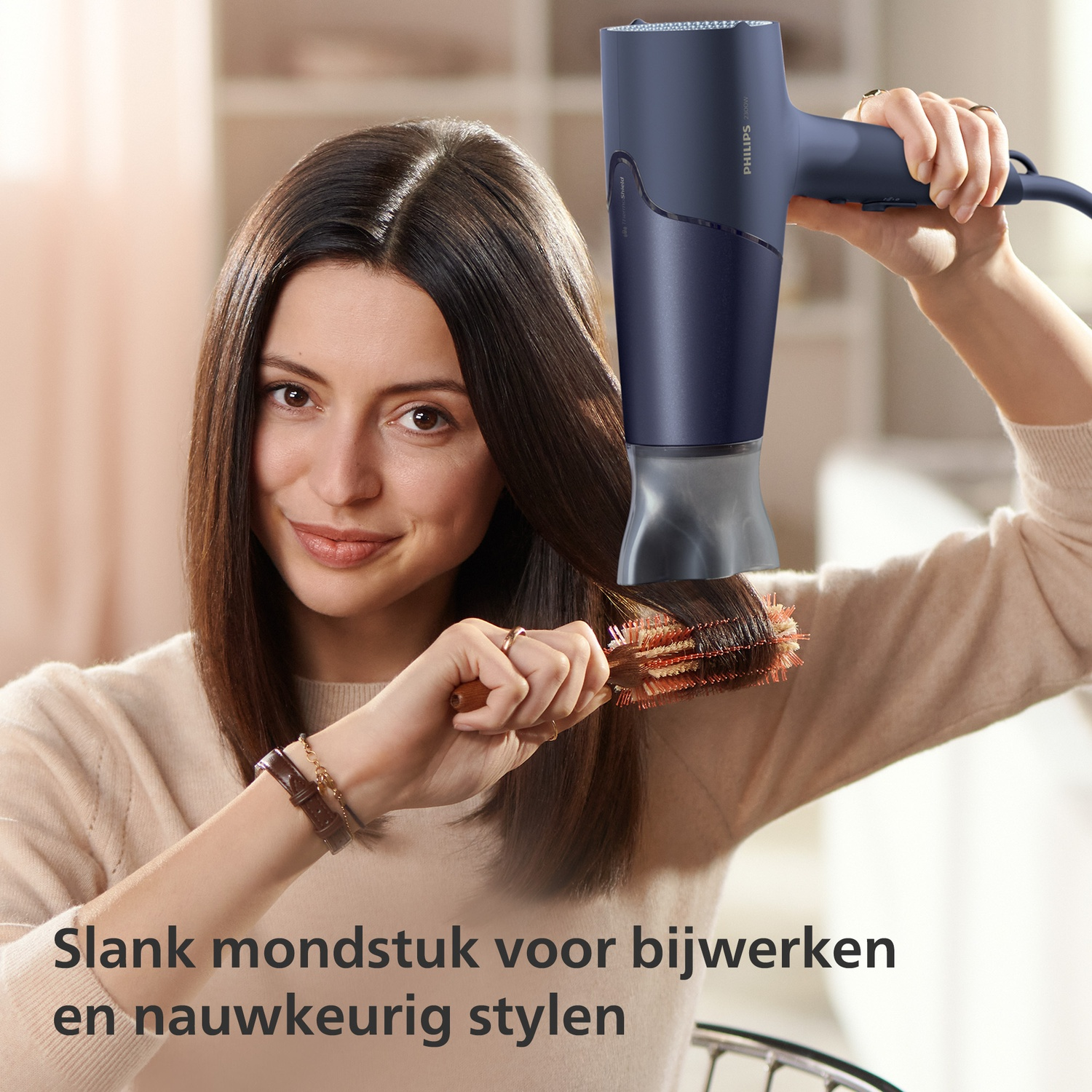 A woman dries her brown hair with a blue hairdryer and a brush.