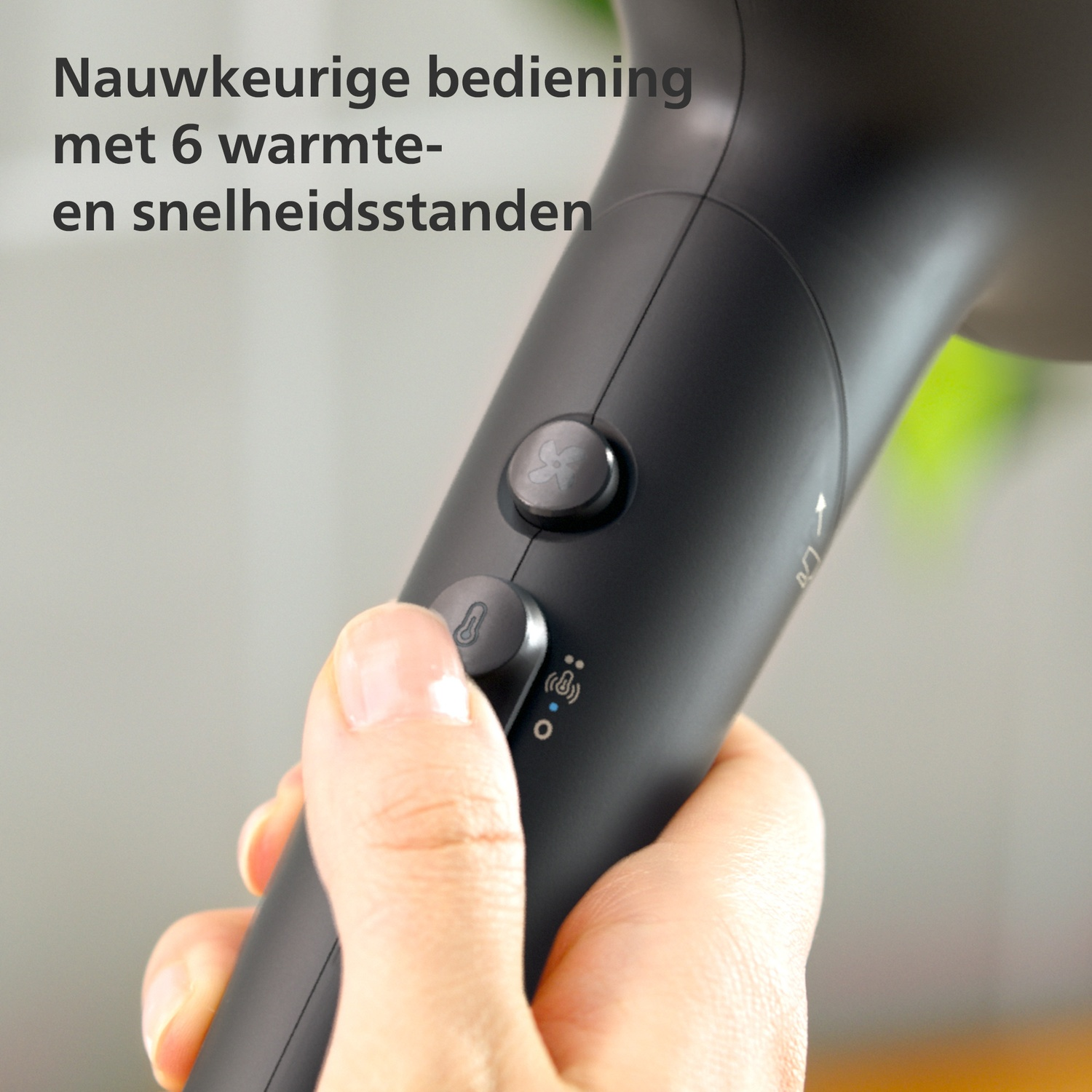 Hand holds black hairdryer with controls and text.