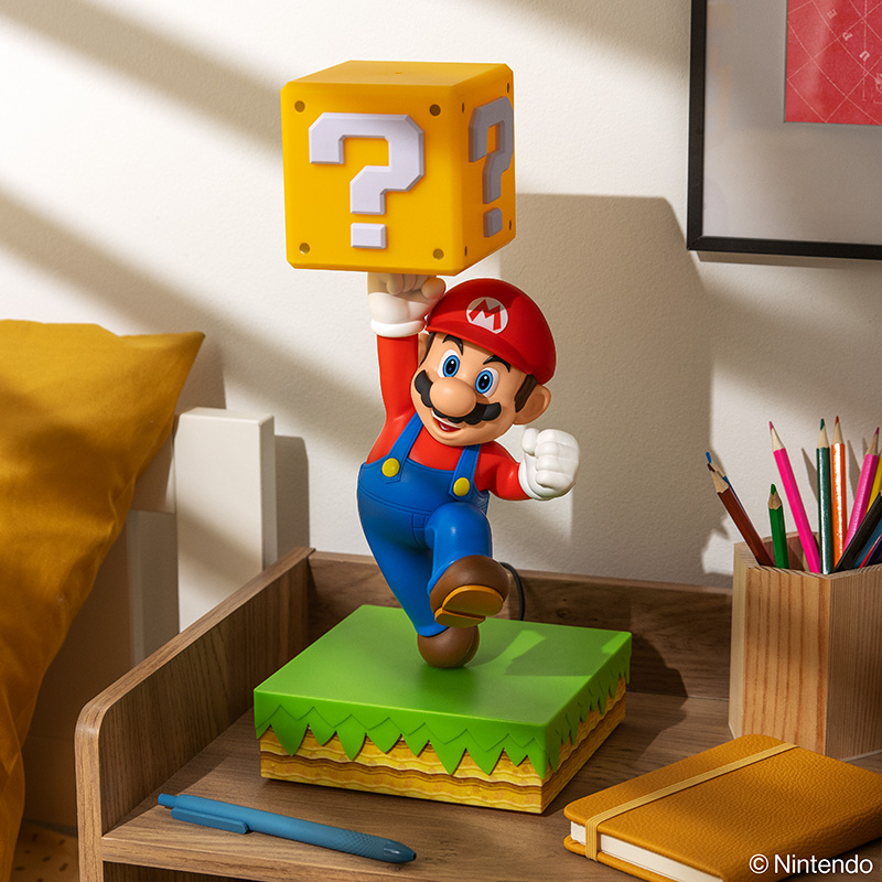 Mario-Figur mit gelbem Fragezeichenblock über dem Kopf auf grüner Plattform.