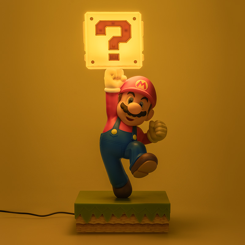 Mario-Figur, die einen beleuchteten Fragezeichenblock hält, steht auf geschichtetem Boden.