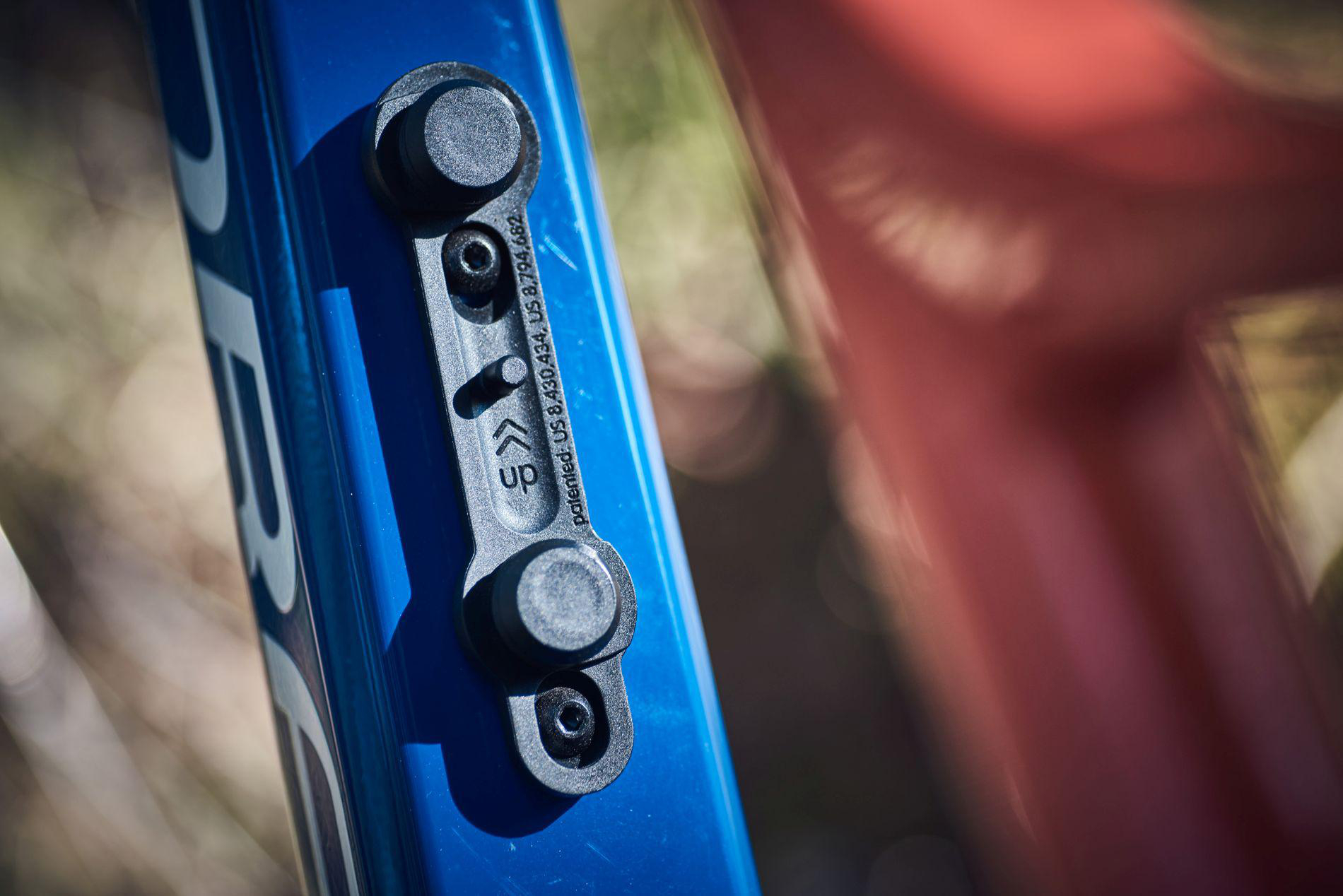 Nahaufnahme einer blauen Fahrradhalterung mit schwarzen Clips und Patentangaben.