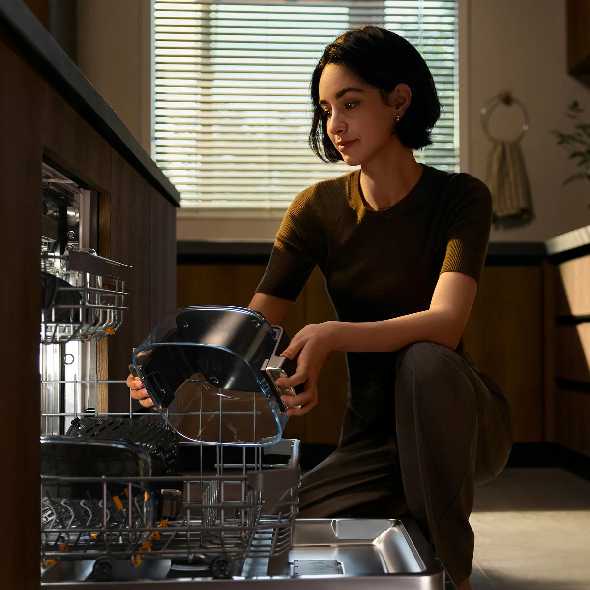Kobieta wkłada naczynia do zmywarki.