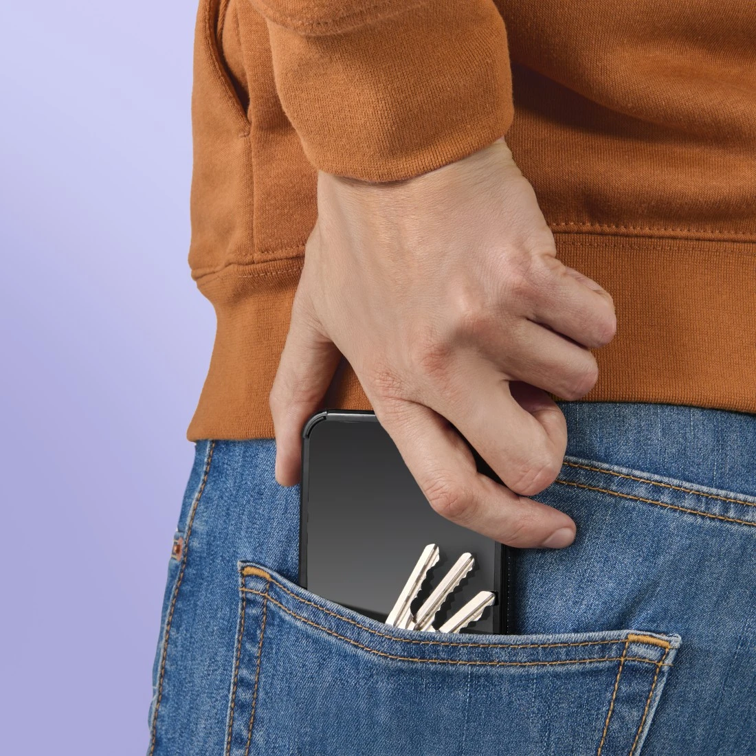 Hand steckt Handy und Schlüssel in Jeans-Tasche.