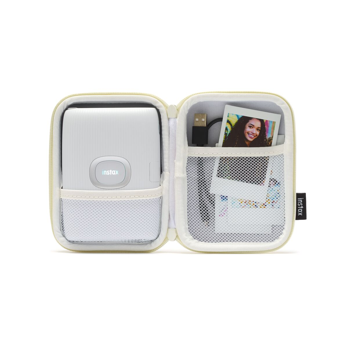 Fotoğraf ve kabloların bulunduğu açık krem rengi bir çantanın içindeki beyaz Instax yazıcı.