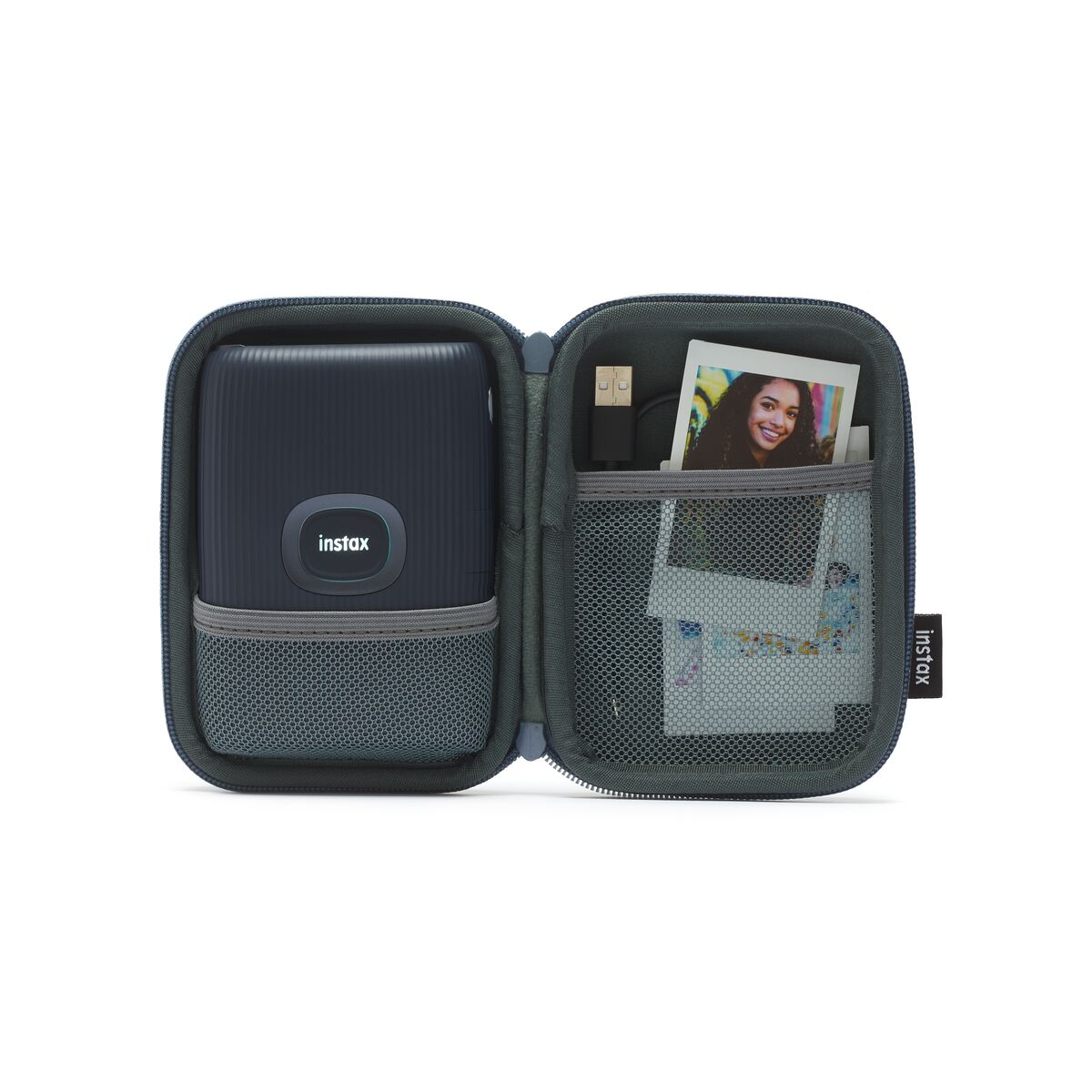 Açık mavi bir çantada, fotoğraflar ve şarj kablosuyla birlikte siyah Instax yazıcı.