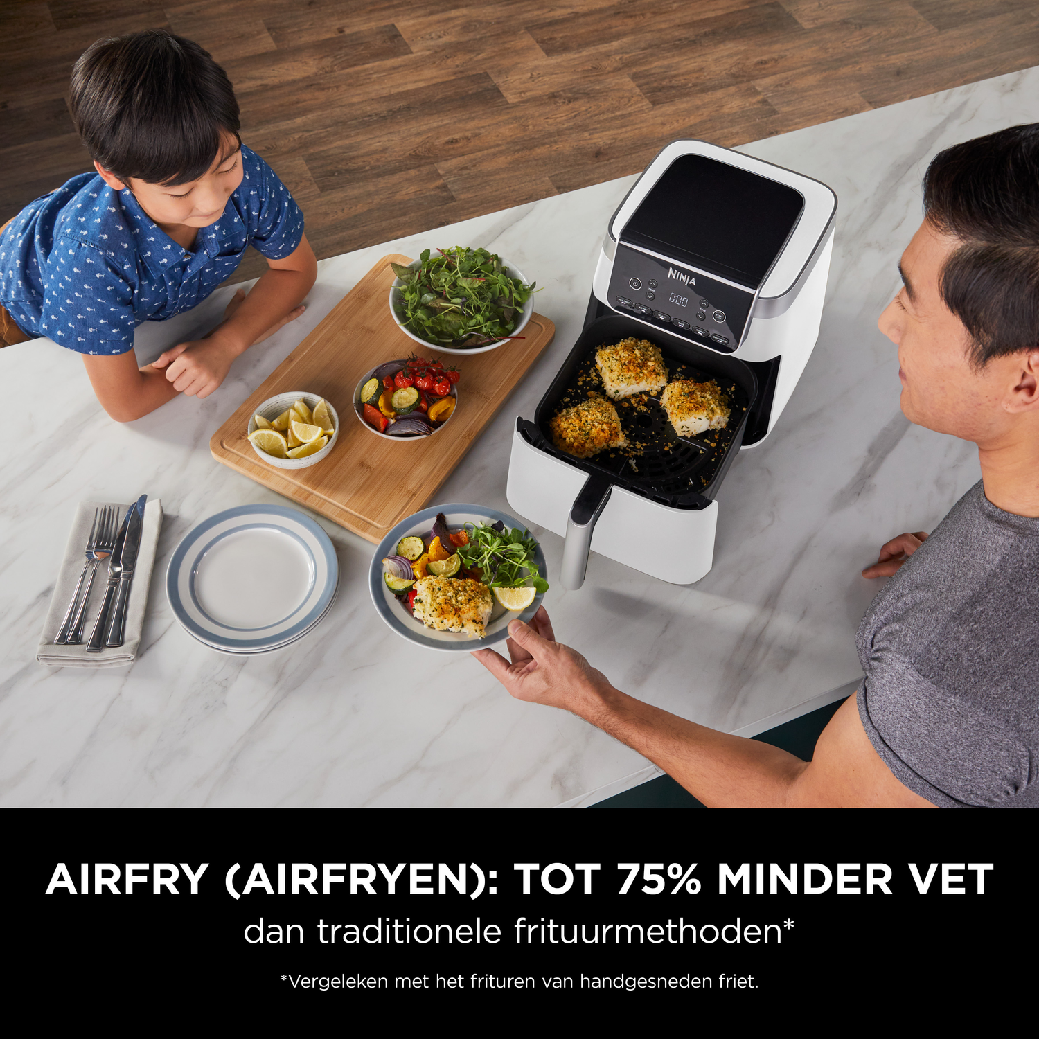Vader en zoon aan tafel met een airfryer en bereid vis.
