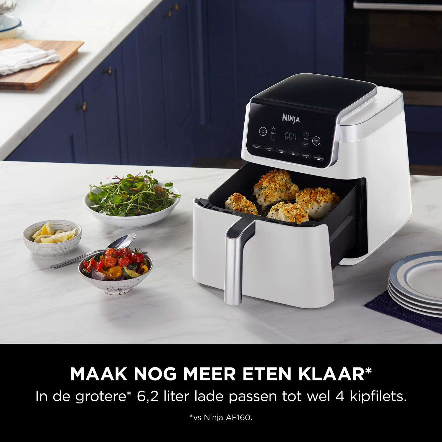 Witte Ninja airfryer met gekookte vis en bijgerechten op een marmeren aanrecht.