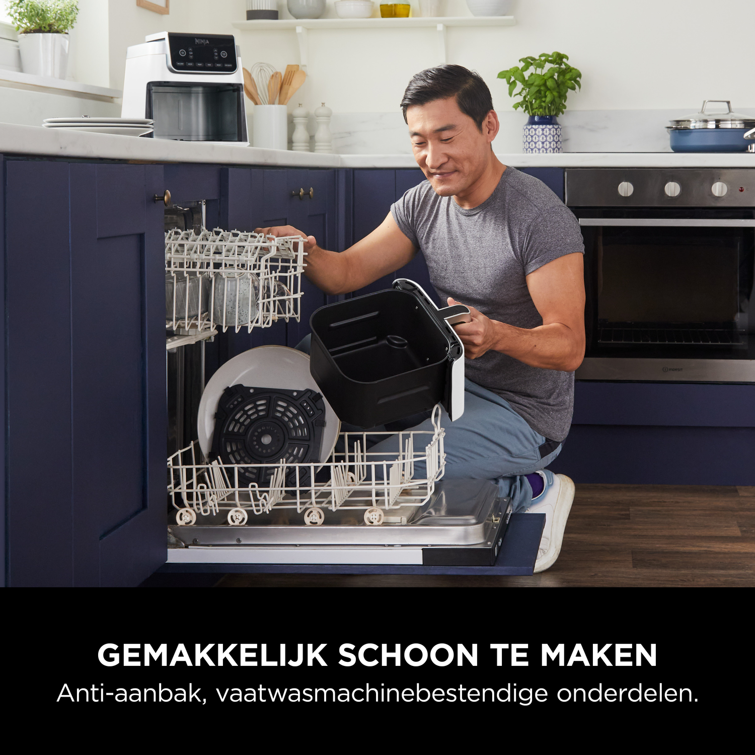 Man laadt airfryer onderdelen in vaatwasser. Keuken op achtergrond.