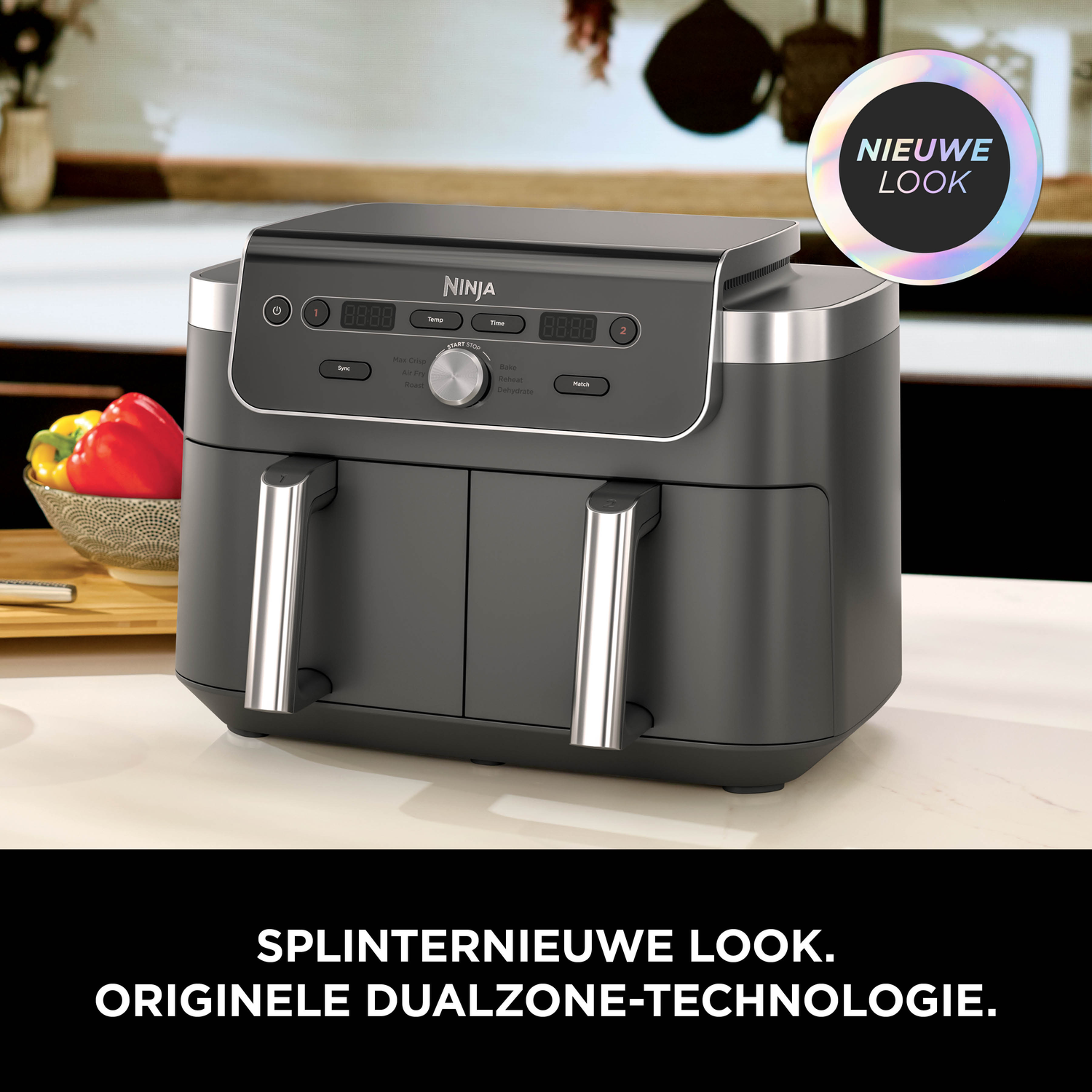 Een zwarte Ninja airfryer met dubbele lades, met paprika's aan de linkerkant.