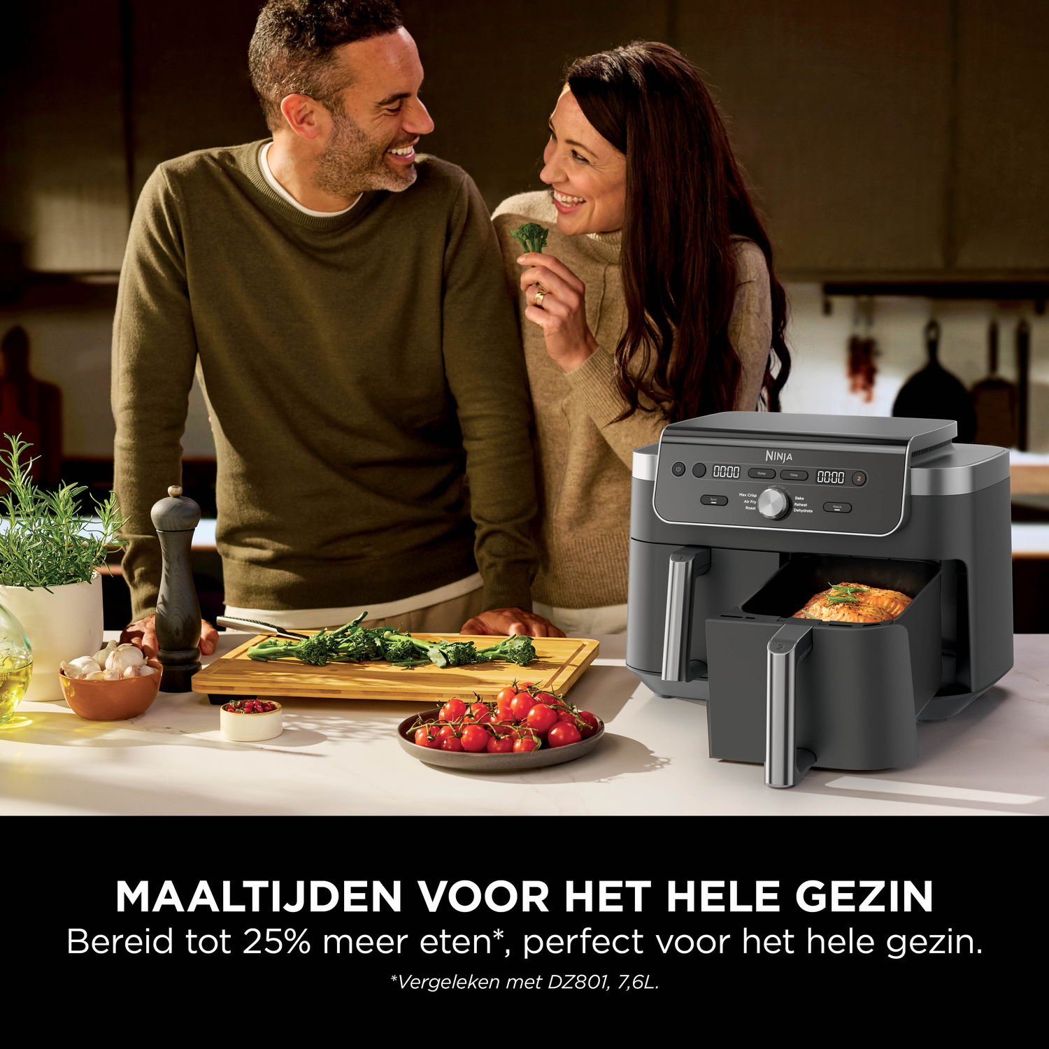 Man en vrouw lachen terwijl ze koken naast een zwarte Ninja airfryer met gebakken zalm.