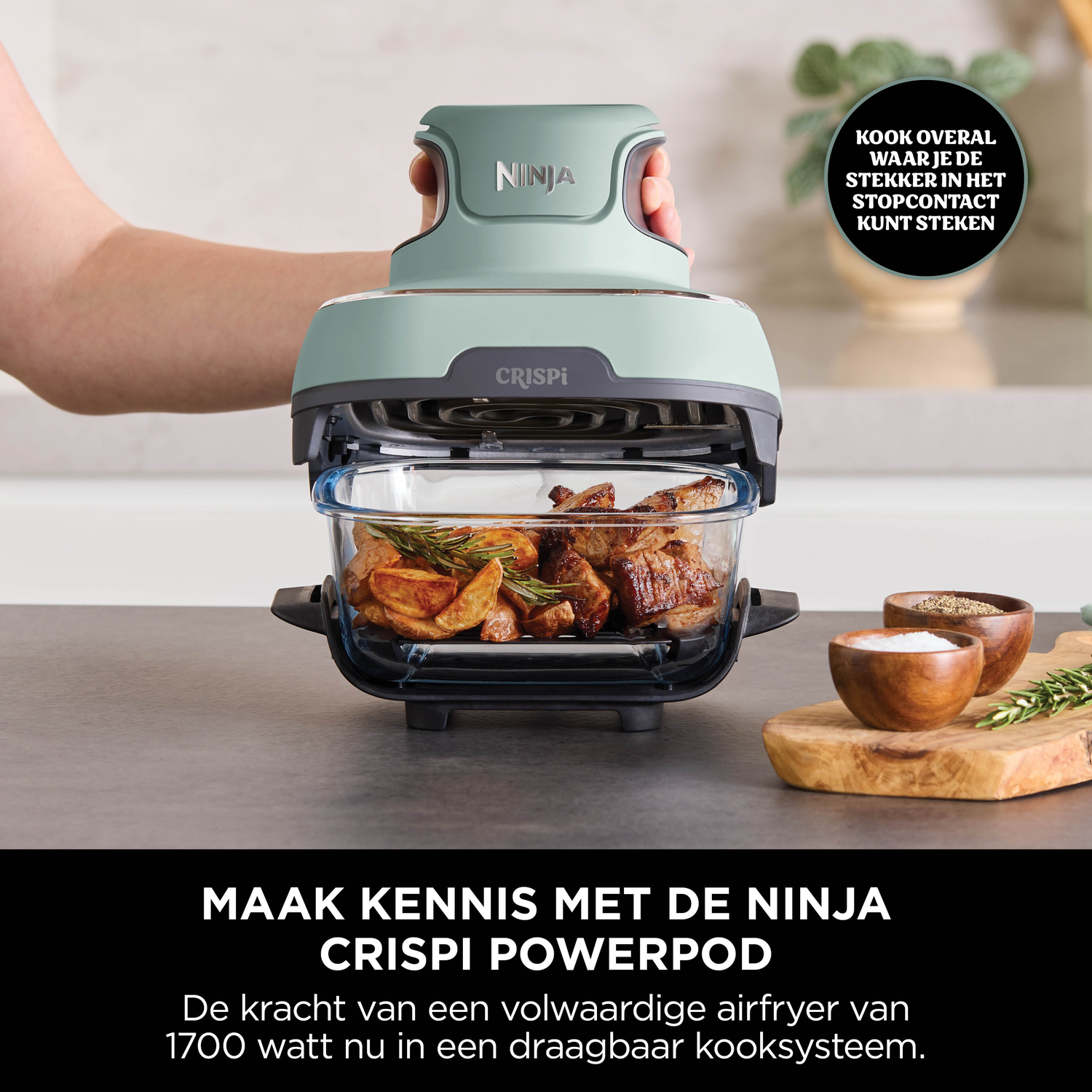 Een muntgroene Ninja Crispi Powerpod boven een glazen schaal met vlees en aardappelen.