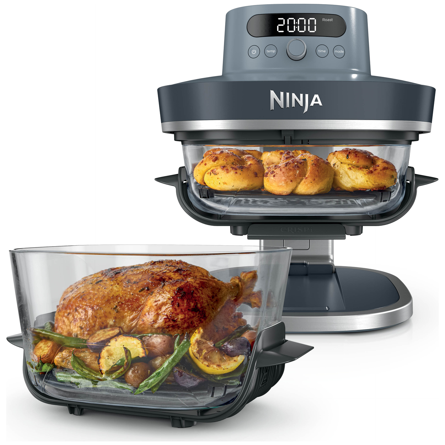 Een Ninja oven met geroosterde kip en groenten in een glazen pan en broodjes in de oven.