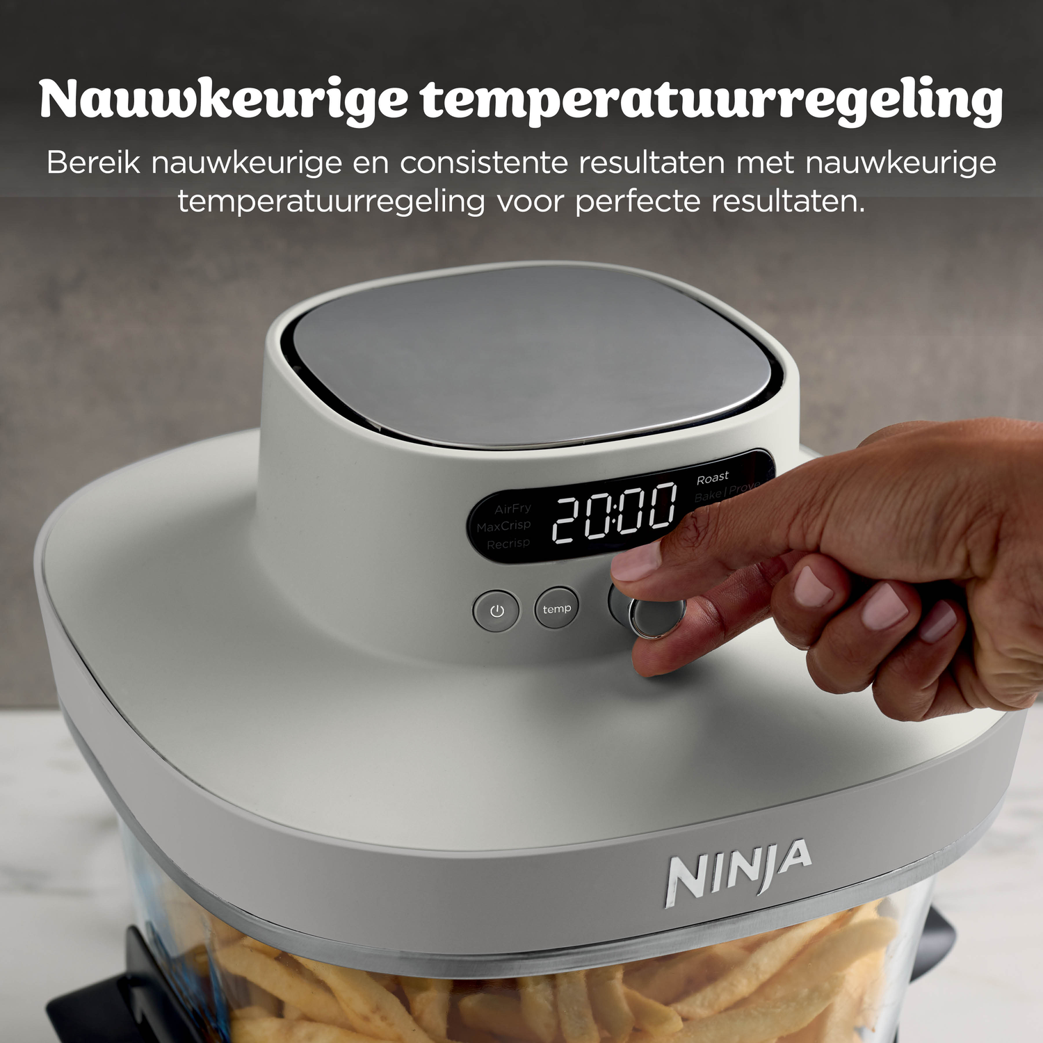 Een hand stelt de tijd in op 20:00 op een grijze Ninja airfryer gevuld met friet.