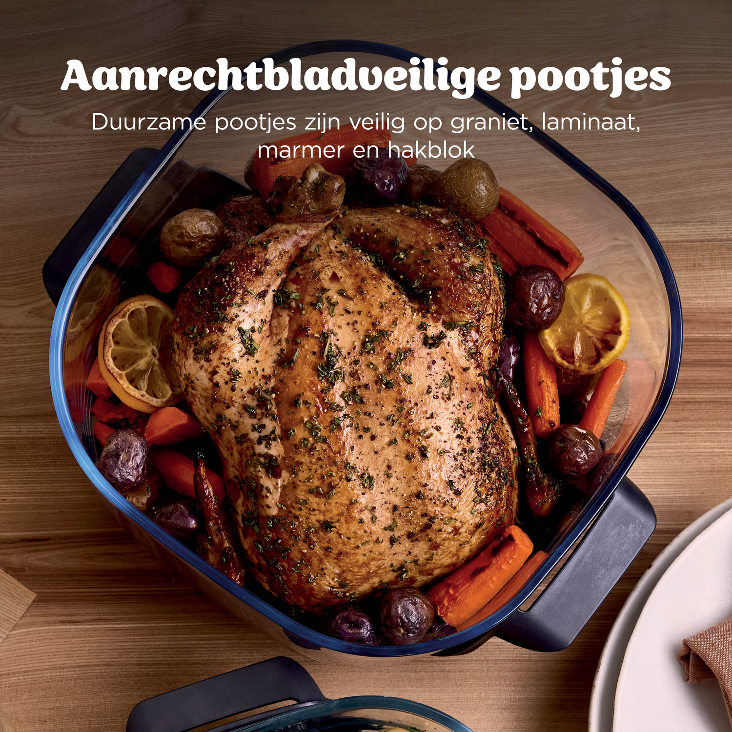 Een geroosterde kip met aardappelen en wortelen in een glazen ovenschaal.