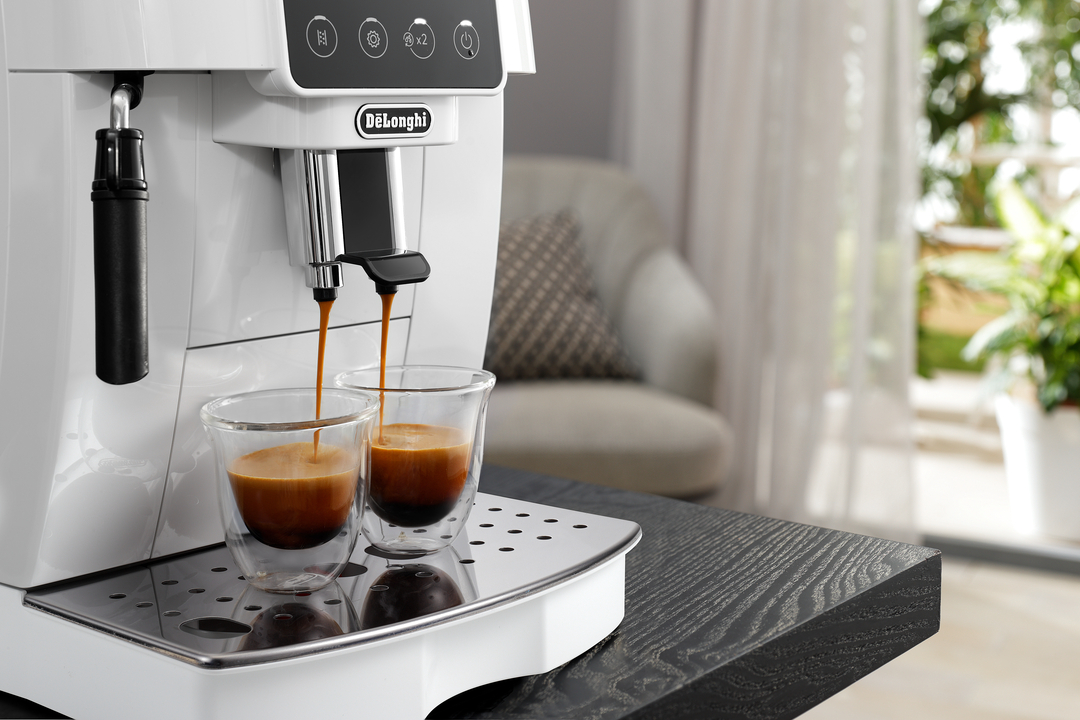 Eine weiße DeLonghi Espressomaschine brüht zwei Tassen Espresso in Glasbecher.