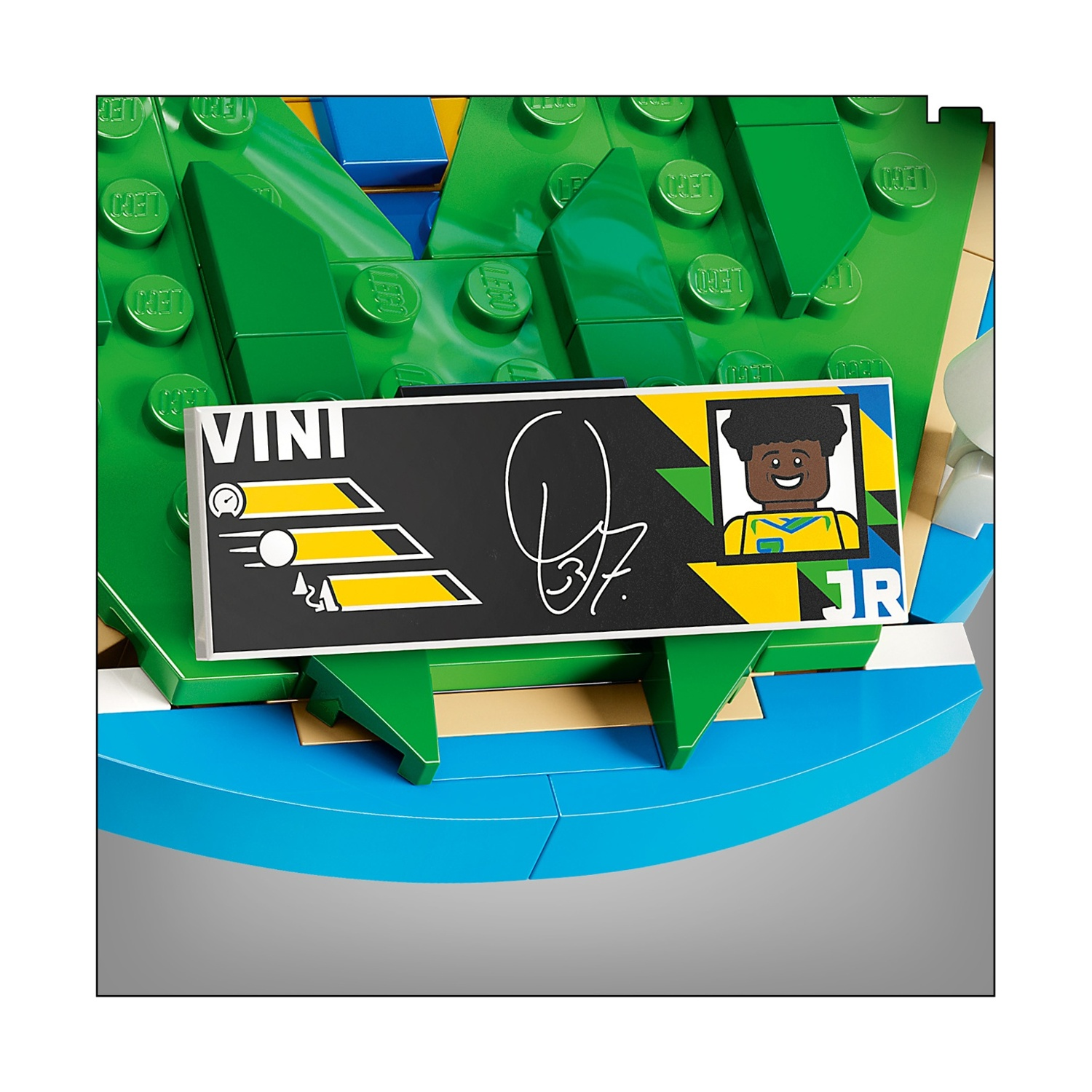 Personaggio Lego con targa Vini Jr., sfondo verde e base blu.