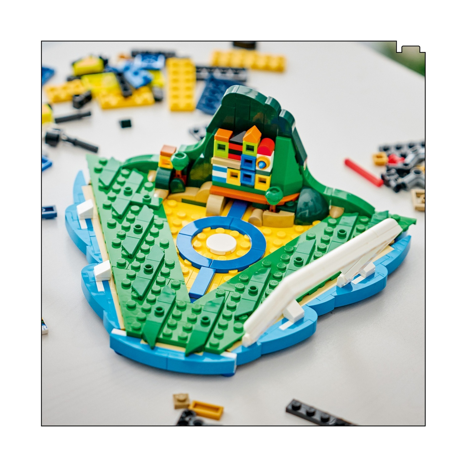 Isola Lego colorata con montagna, casa e acqua blu.