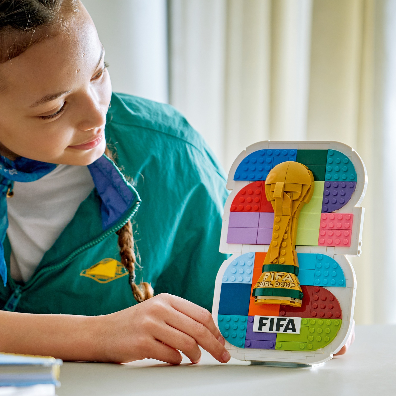 Una ragazza in giacca verde guarda una replica Lego del trofeo della Coppa del Mondo FIFA.