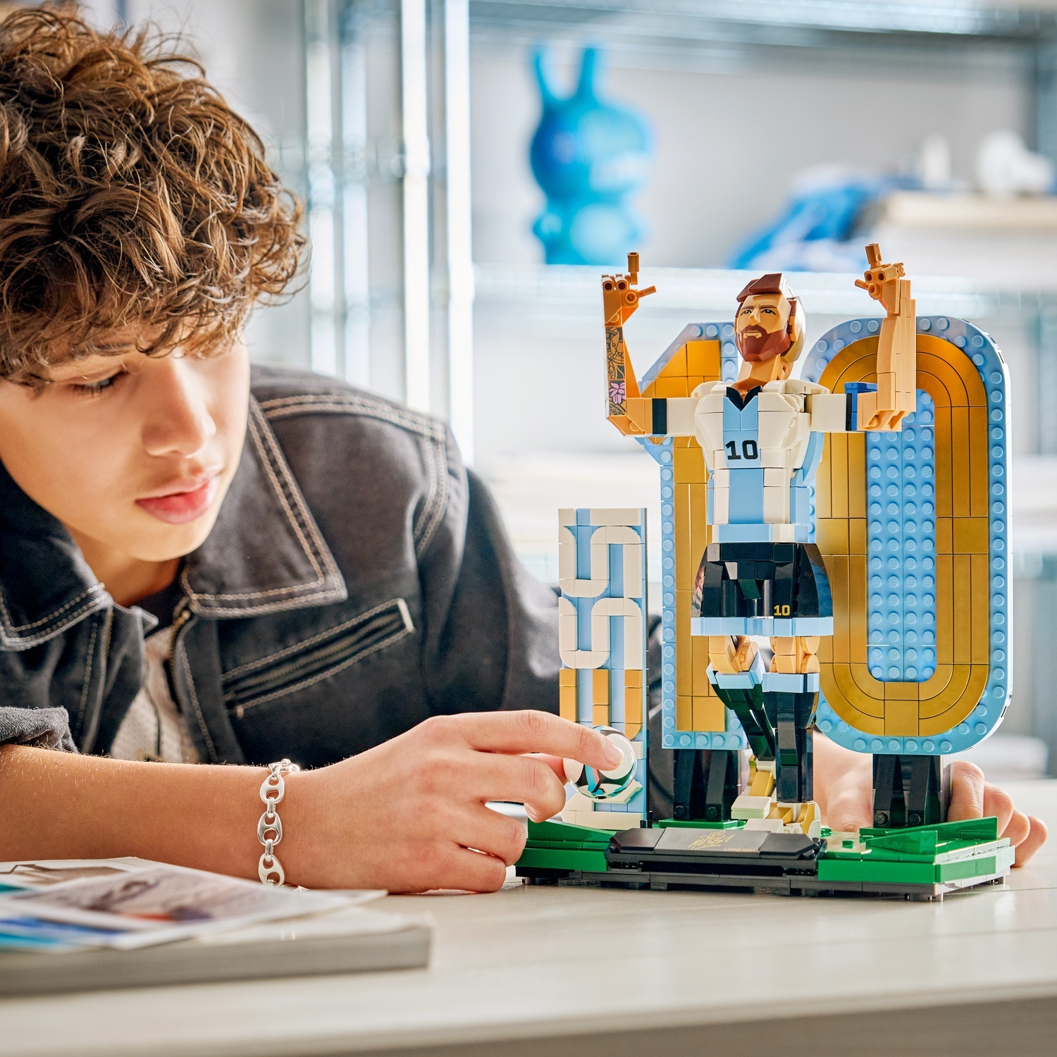 Ragazzo costruisce statuetta Lego di Messi con numero 10 e trofeo.