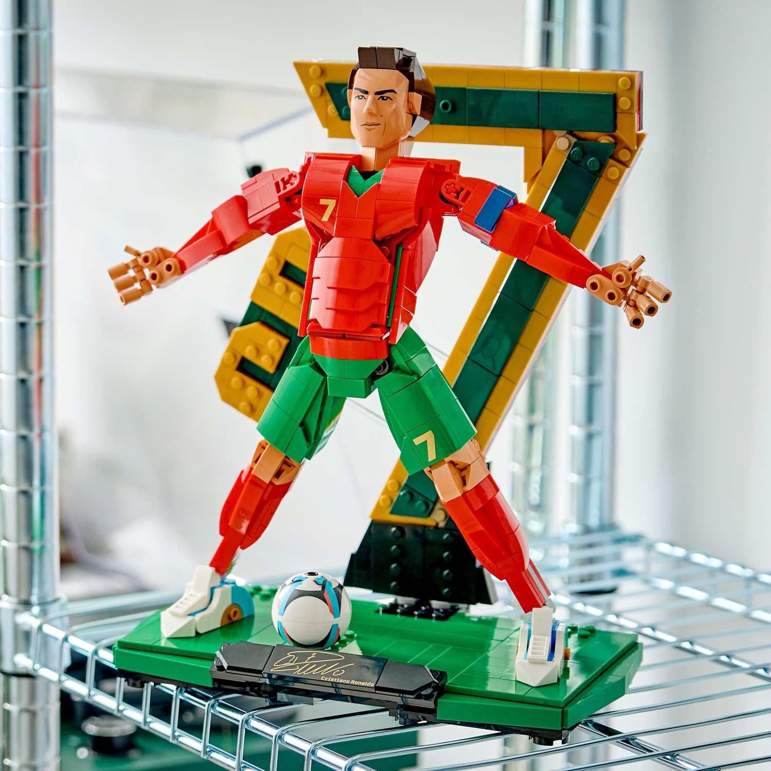 Un calciatore Lego rosso e verde con il numero 7 si erge davanti a un grande numero 7 Lego.