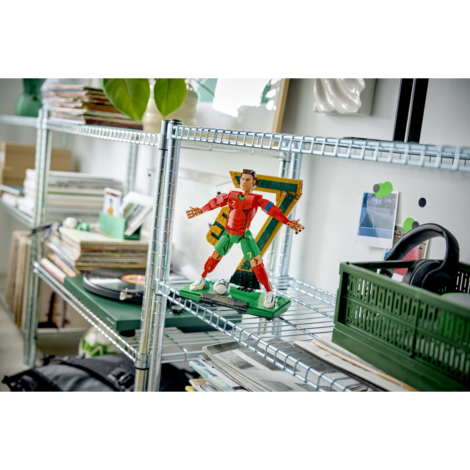 Un calciatore Lego rosso e verde si trova su una base verde con un pallone.